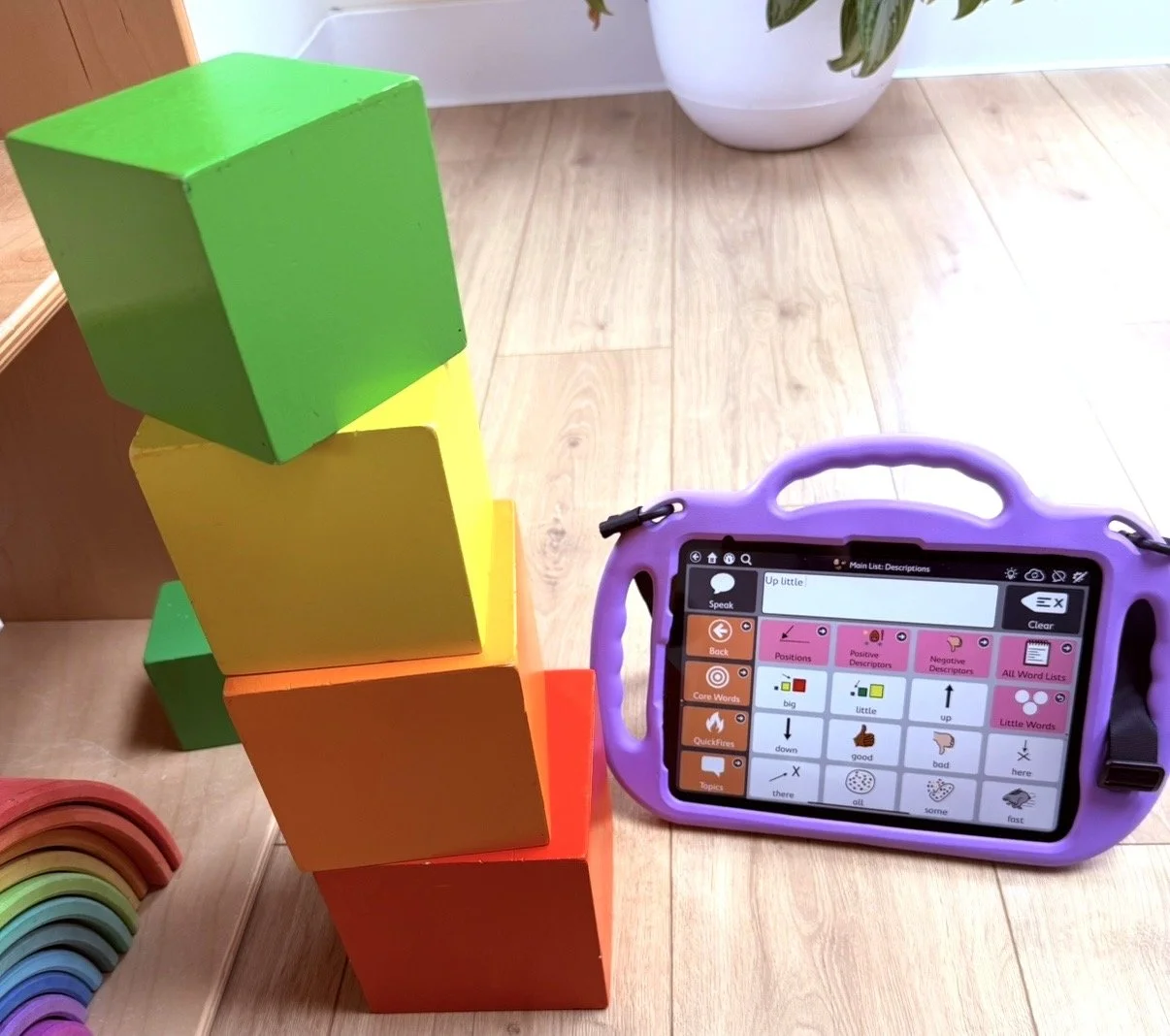 Pediatric soeech therapy setup with colorful bloks and AAC device for communication support.