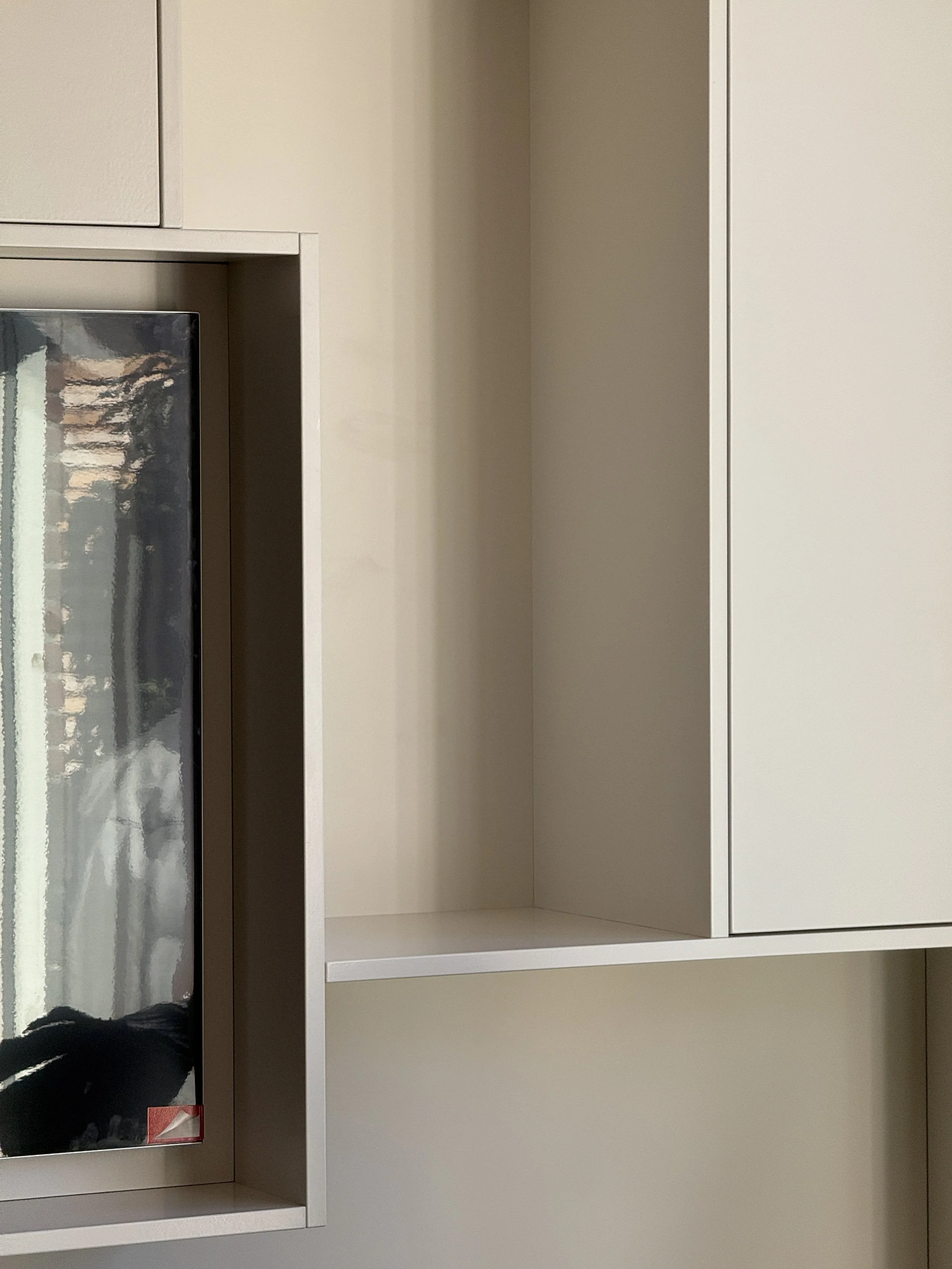 Leeg wit kastje en een glasdeur met reflectie in een muur.