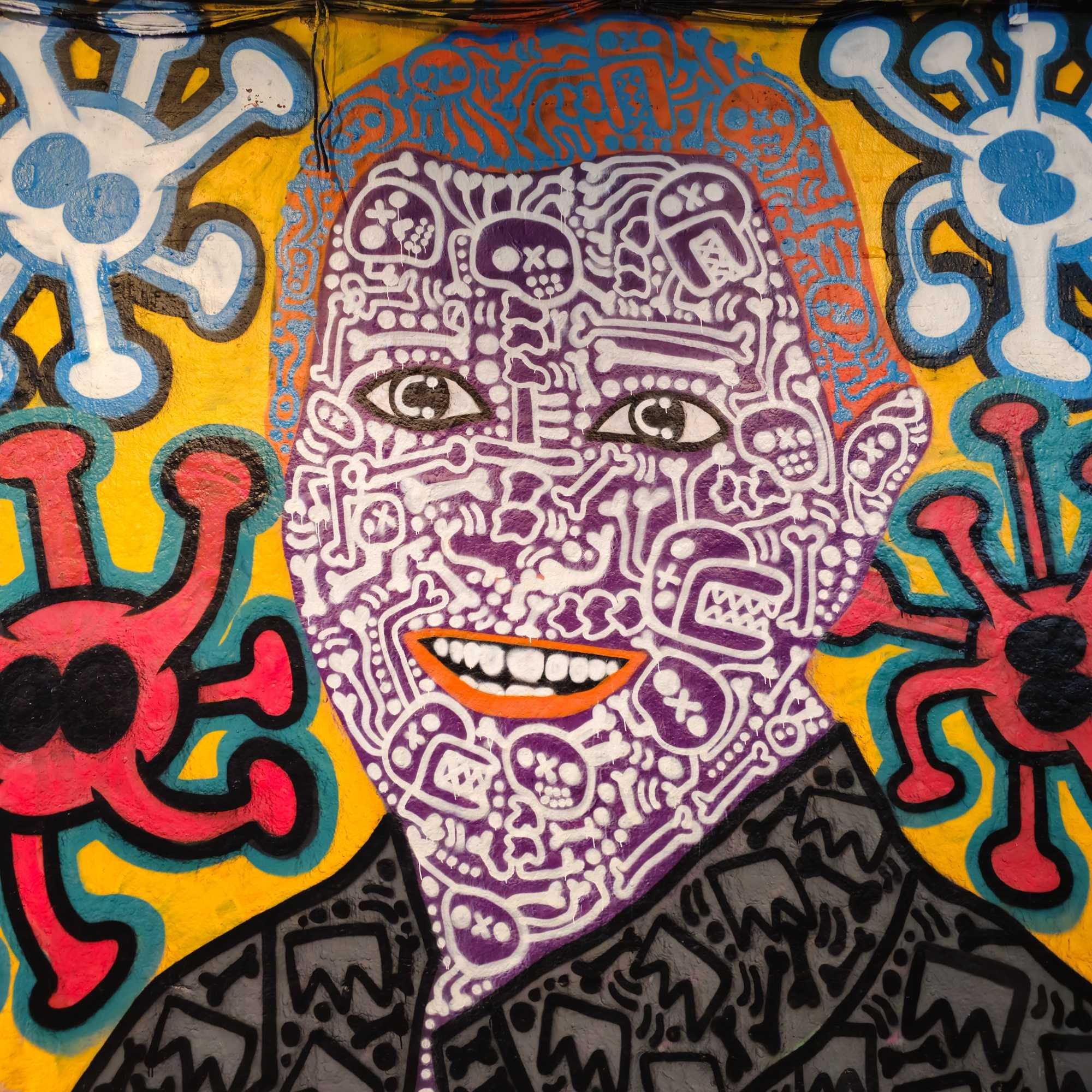 A dynamic graffiti mural bursting with colour and personality, featuring intricate facial details against a bright yellow background. Captured by Daines Royal Limited to showcase authentic urban artistry, creative photography, and modern marketing in