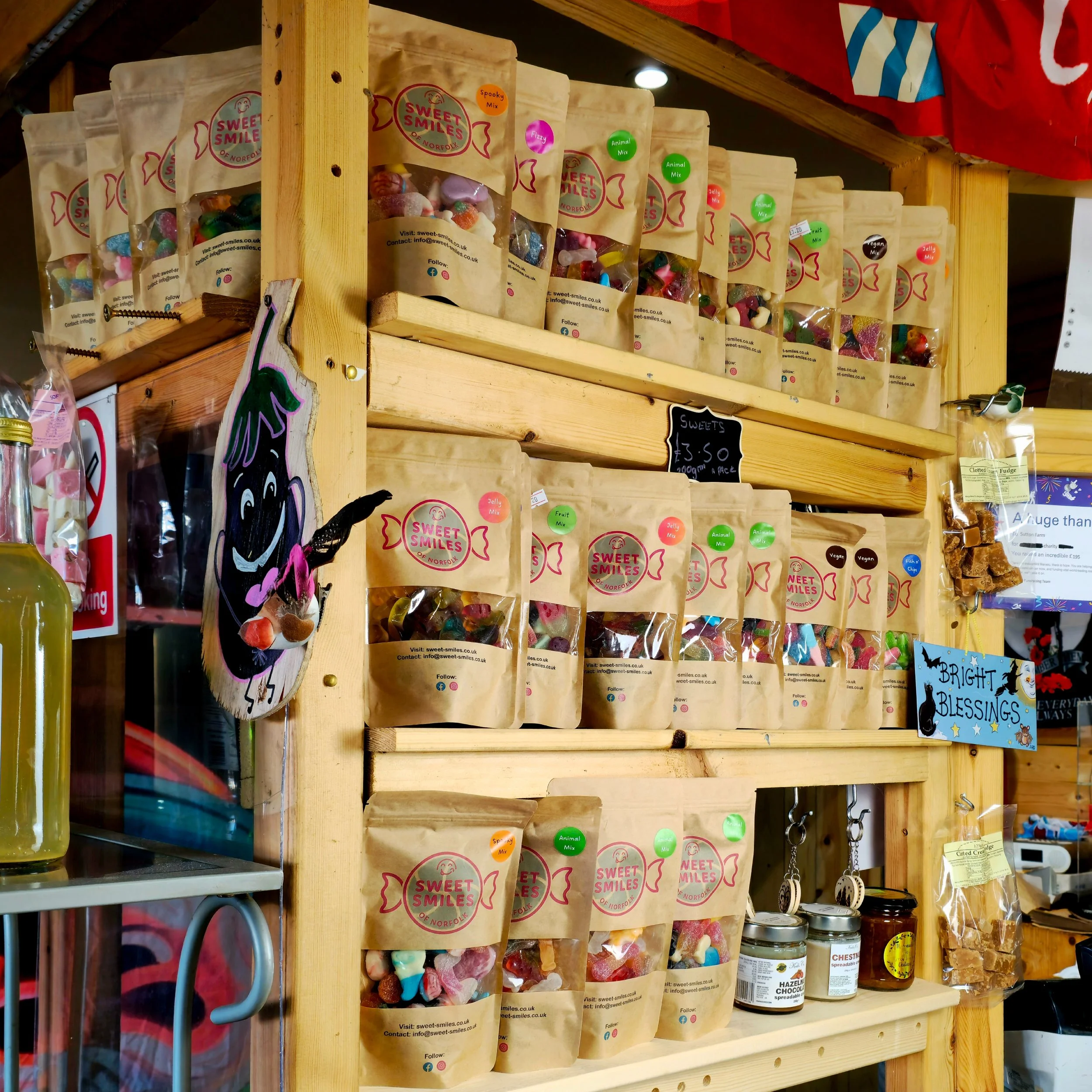 A joyful shelf filled with handmade sweets and local preserves, framed by rustic wood and cheerful signage. The packaging design, natural lighting, and tactile materials come together to evoke a sense of nostalgia and craftsmanship—proof that even si