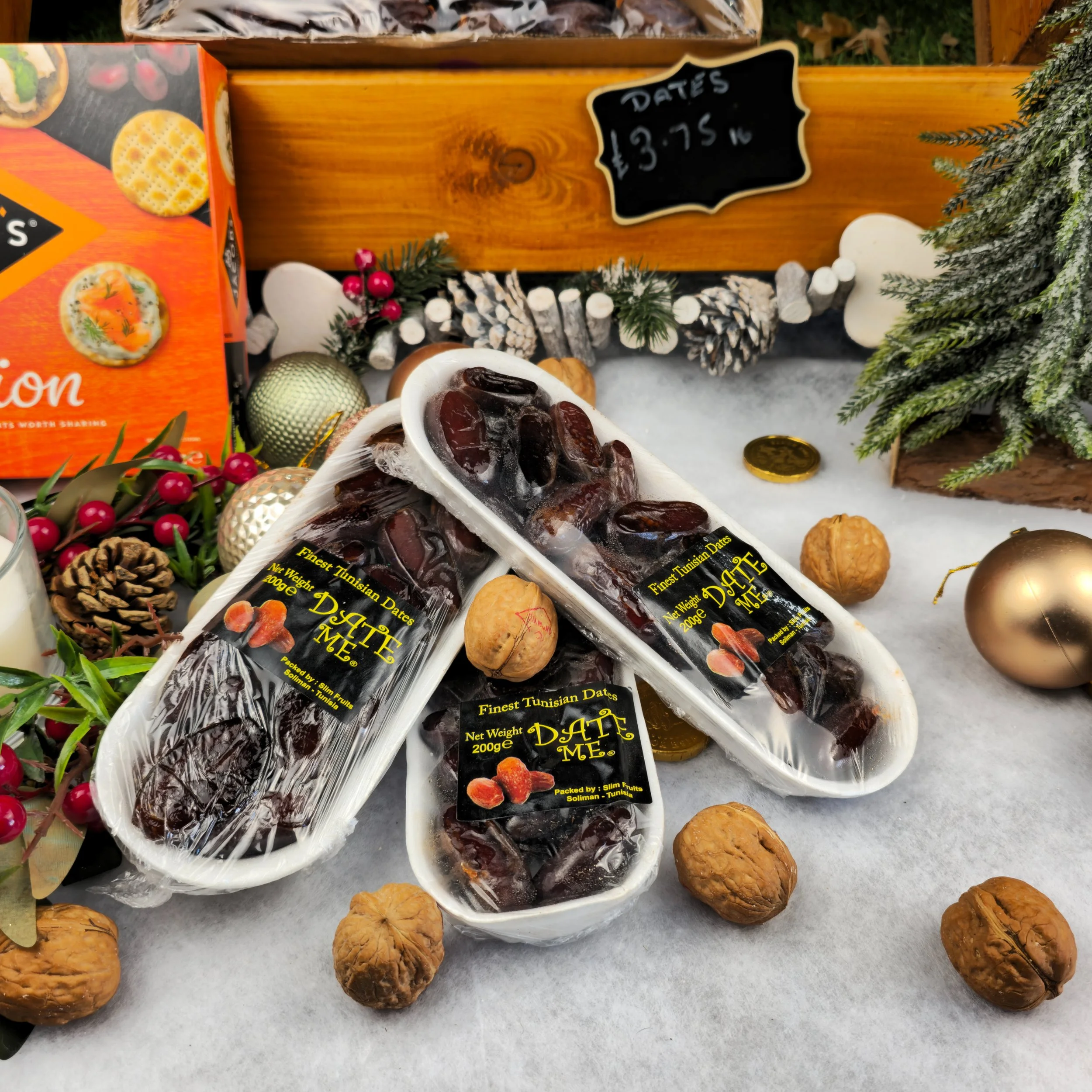 Finest Tunisian dates, framed by walnuts, pinecones, and warm Christmas tones. The natural textures and golden highlights create a feeling of festive abundance. Every detail—from the smooth surface of the fruit to the soft snow-white backdrop—evokes 