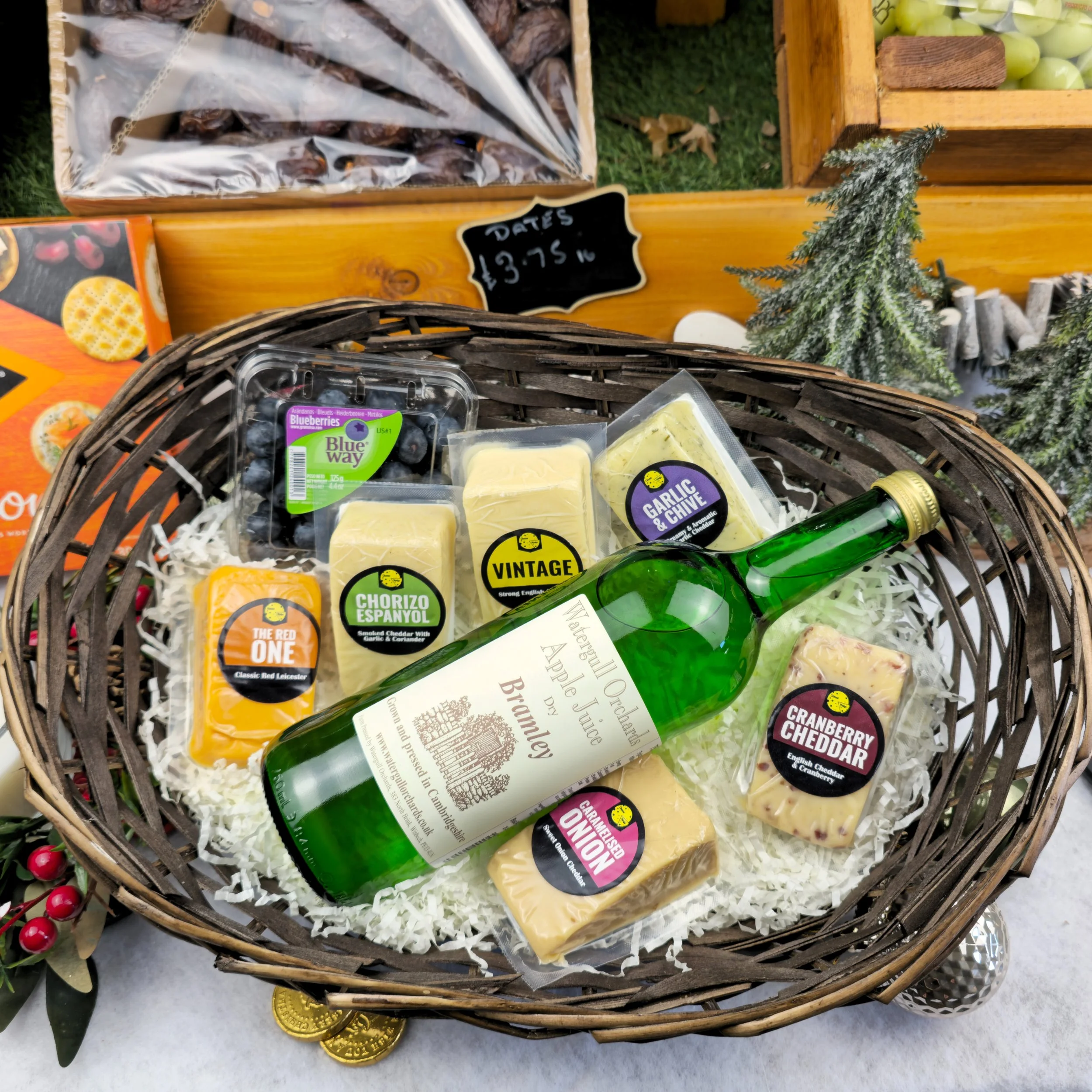 A classic Lincolnshire gift basket pairing hand-cut cheeses with crisp apple juice. The natural grain of wicker, paired with the soft texture of straw, frames a celebration of flavour and locality. It’s a still life of true English countryside charac