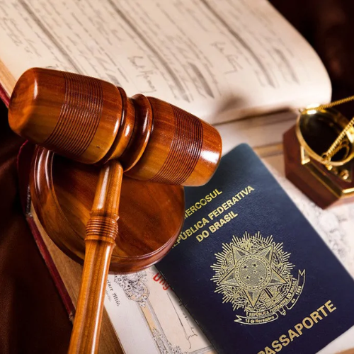 Martelo de juiz, passaporte brasileiro, documentos e uma luneta sobre uma mesa.