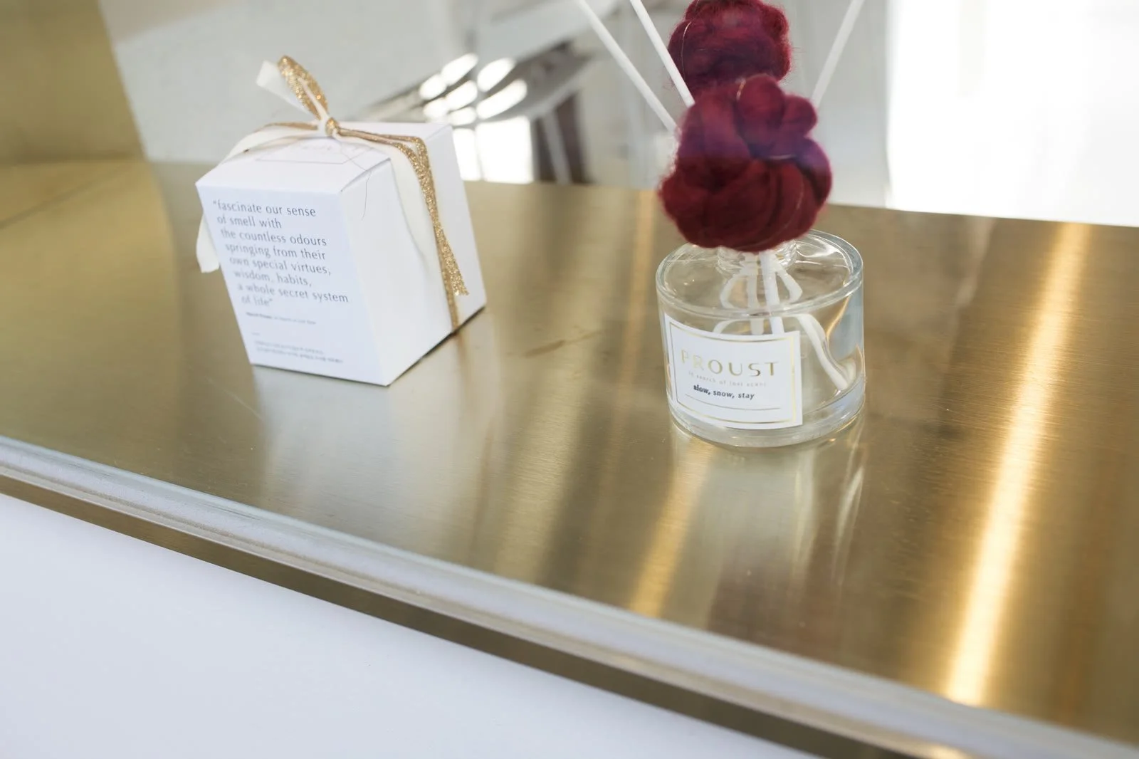 Gift box and flower vase on a brass shelf