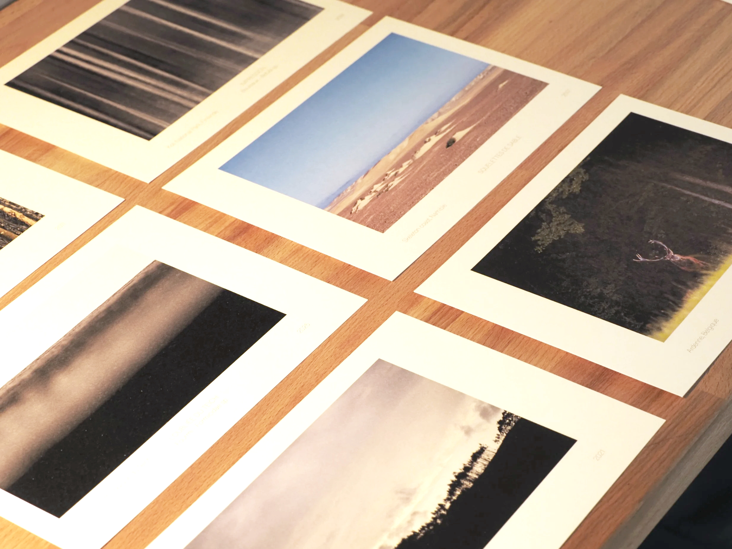 Collection de photos de paysages variés disposées sur une table en bois