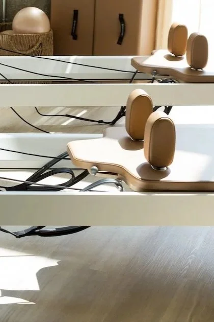 Two wooden sit-up benches with back support on a white table, in a room with a cabinet and a lamp in the background.