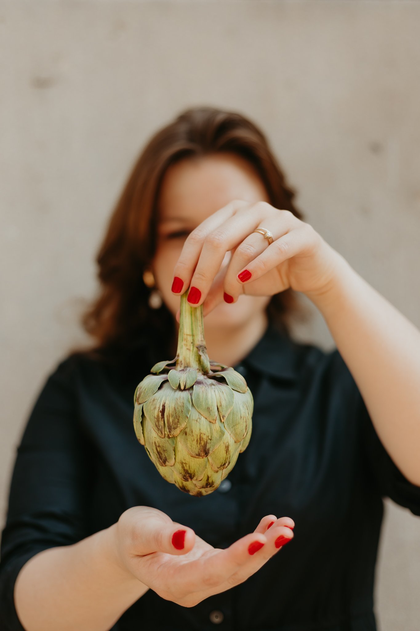 A woman with long brown hair, dressed in a light pink outfit, sitting on a medical examination table with her knees bent, placing a bag on the table.