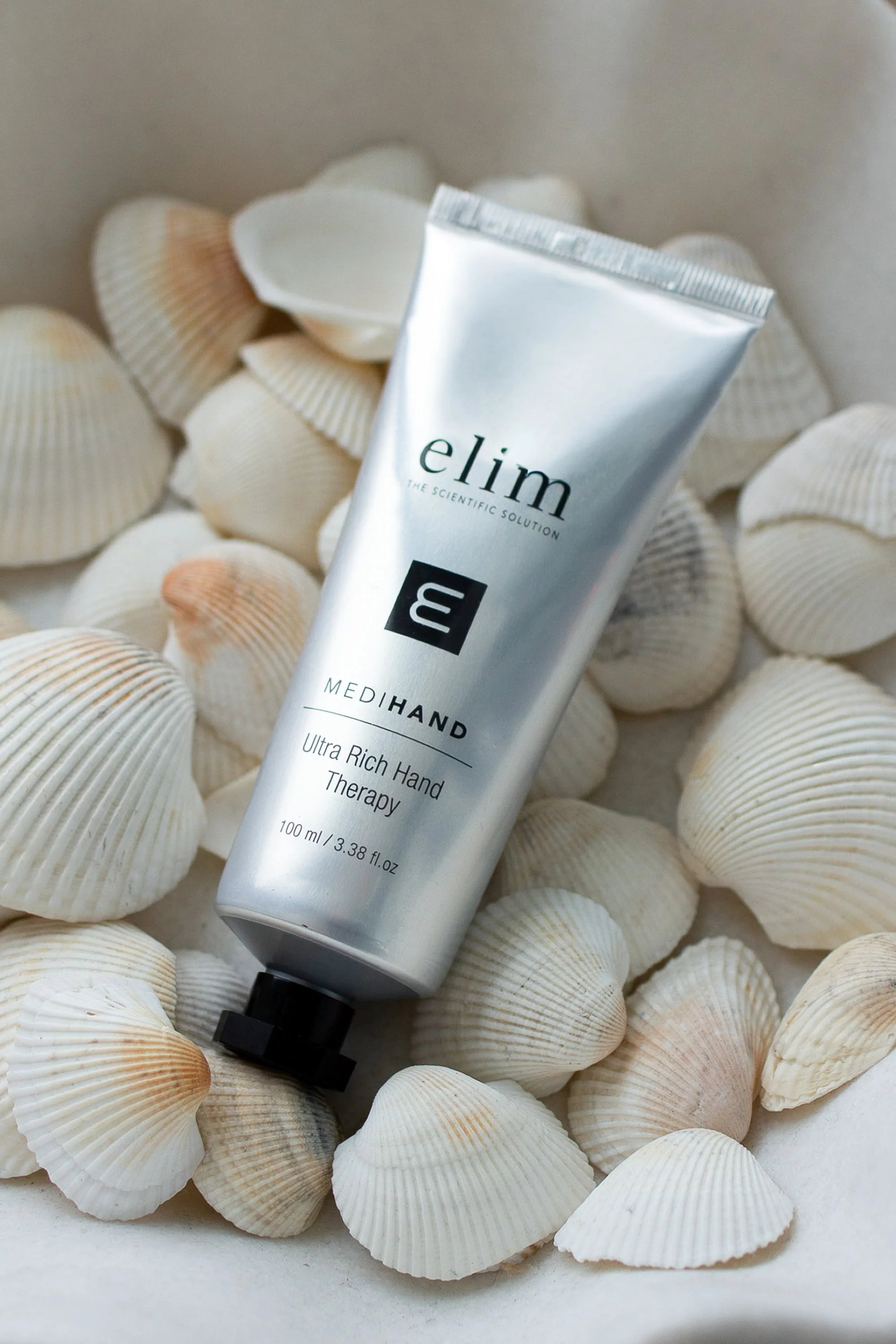 A tube of elim Ultra Rich Hand Therapy cream surrounded by seashells.