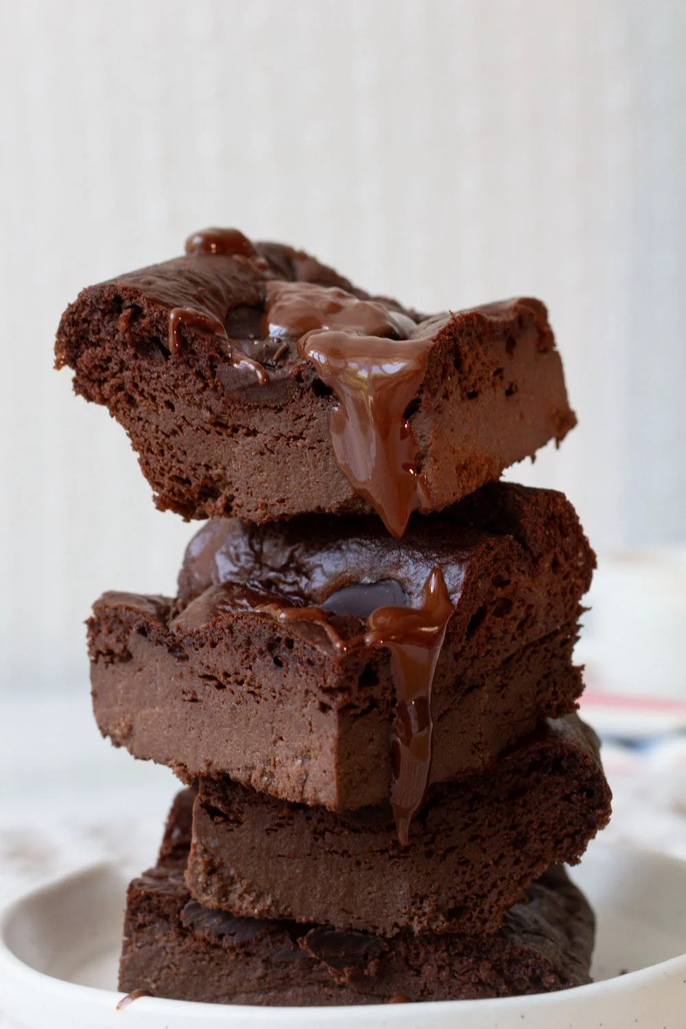 Stacked chocolate brownies topped with melted chocolate.