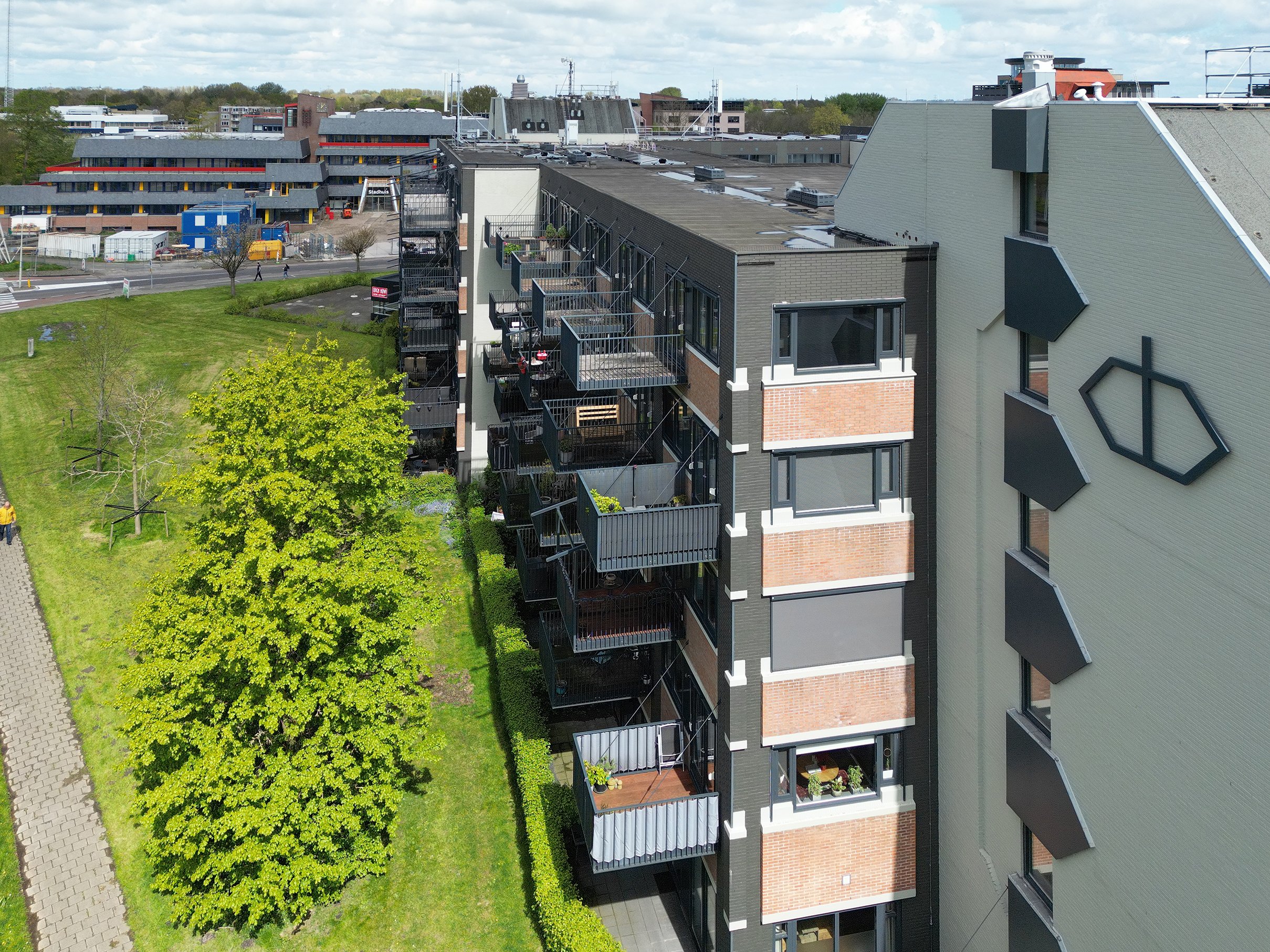 Uitzicht op een binnenstad met moderne appartementen en een groen park met bomen.
