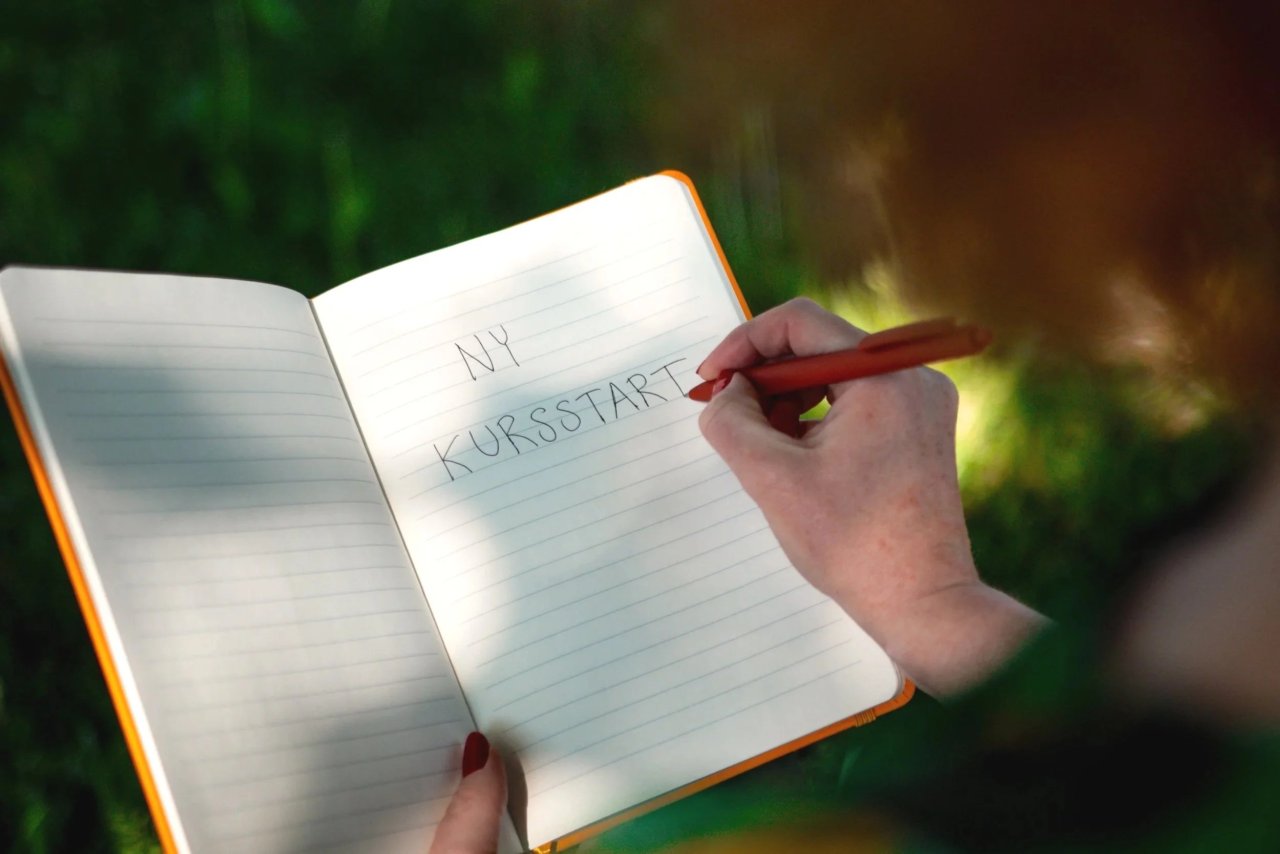 Någon skriver i en bok inför kursstart i en skrivkurs