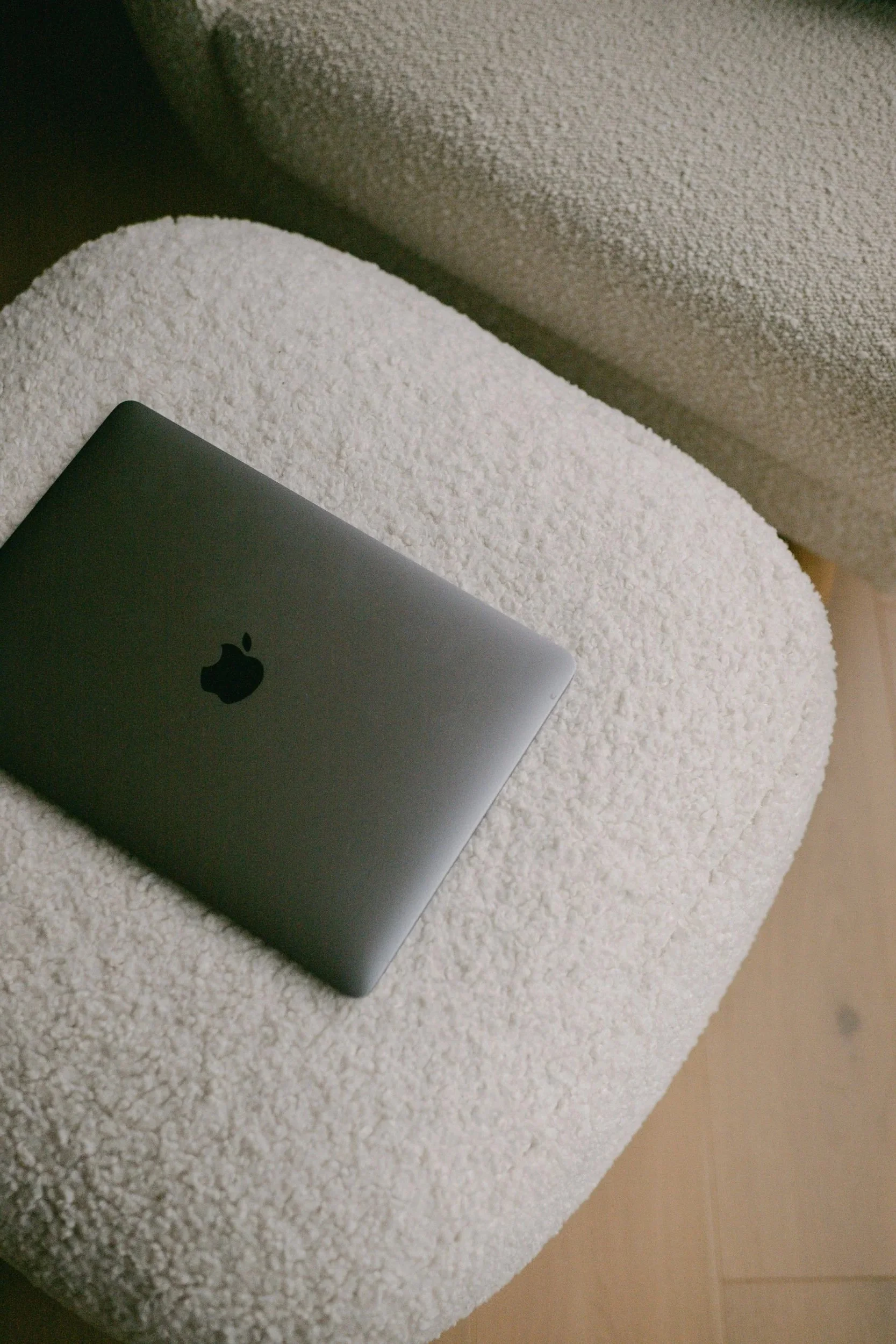 A silver laptop partially placed on a white textured surface, with a light-colored background.
