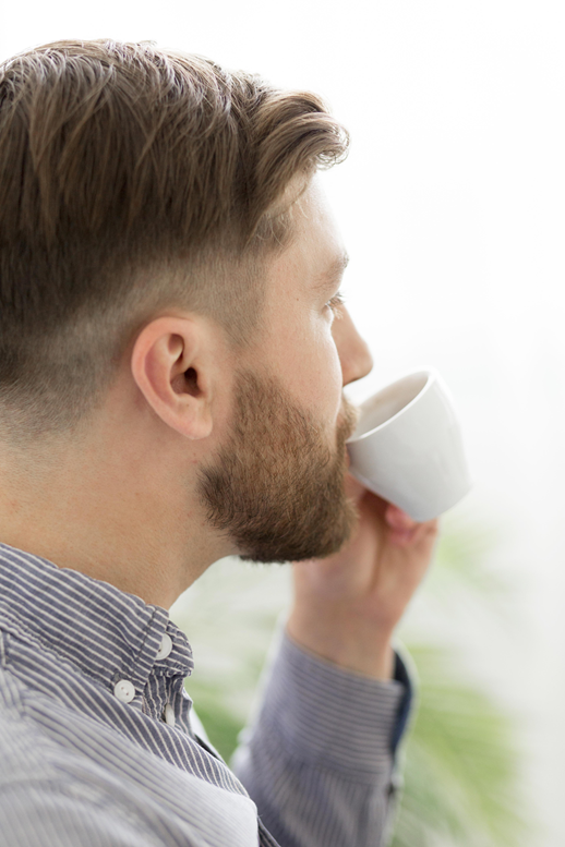 Uomo che beve caffè — alopecia androgenetica e caffeina, tricologia Roma