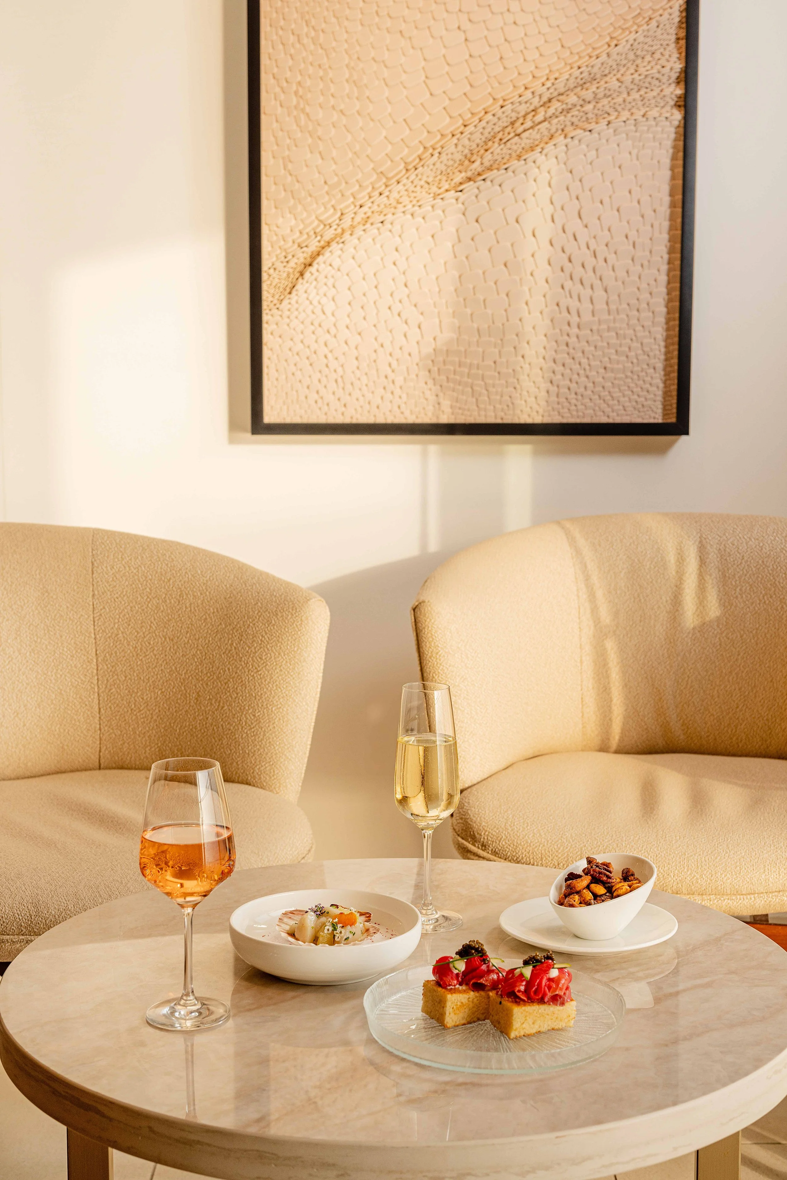 A cozy living room with a round marble coffee table set with two glasses of wine. Photo by Summerside Creative A Hotel Social Media & Creative Agency Serving Hospitality Brands