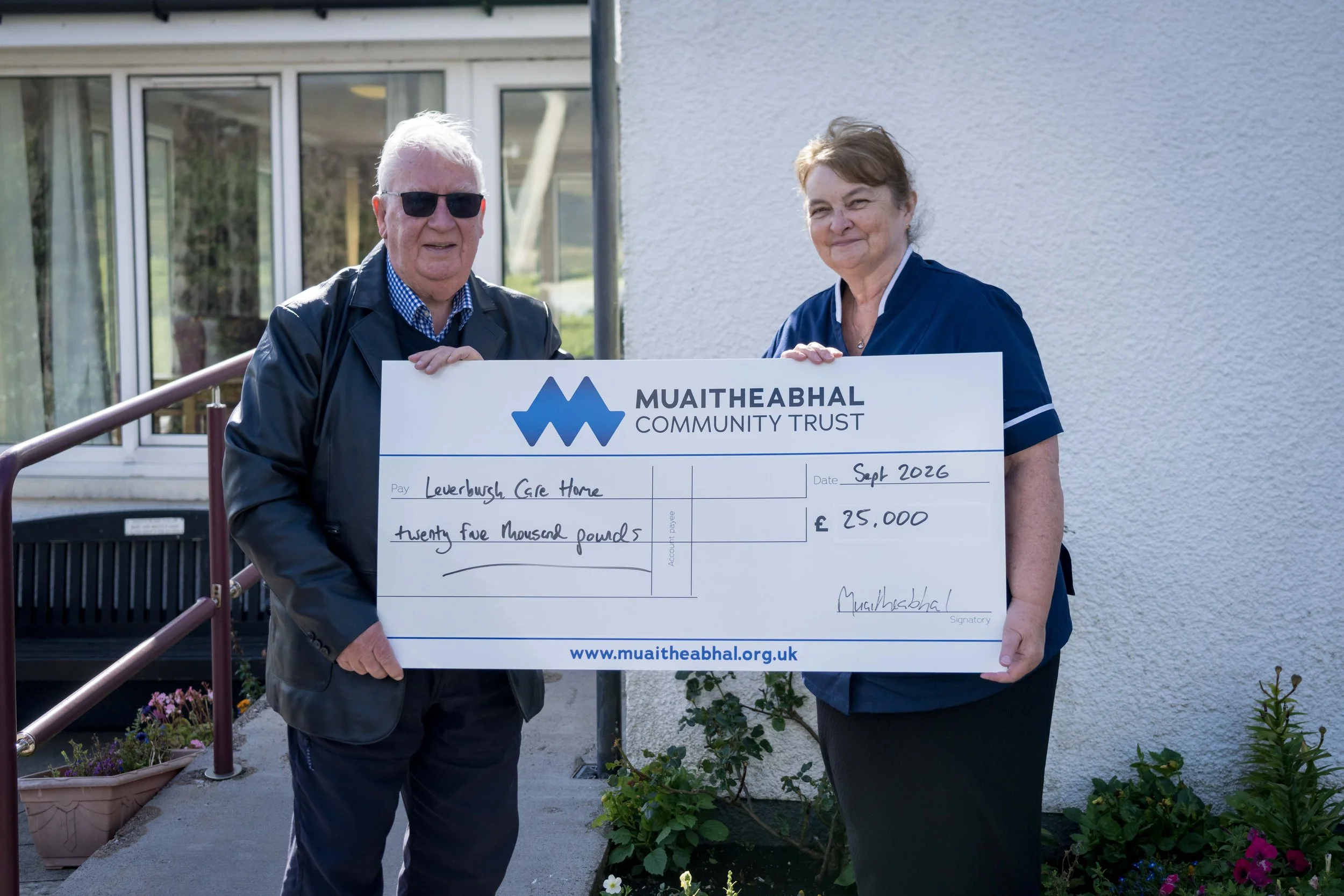 Donnie Morrison, Board Member of Muaitheabhal Community Trust, presents a cheque for £25,000 to Isabel Campbell, Manager of Leverburgh Care Home.