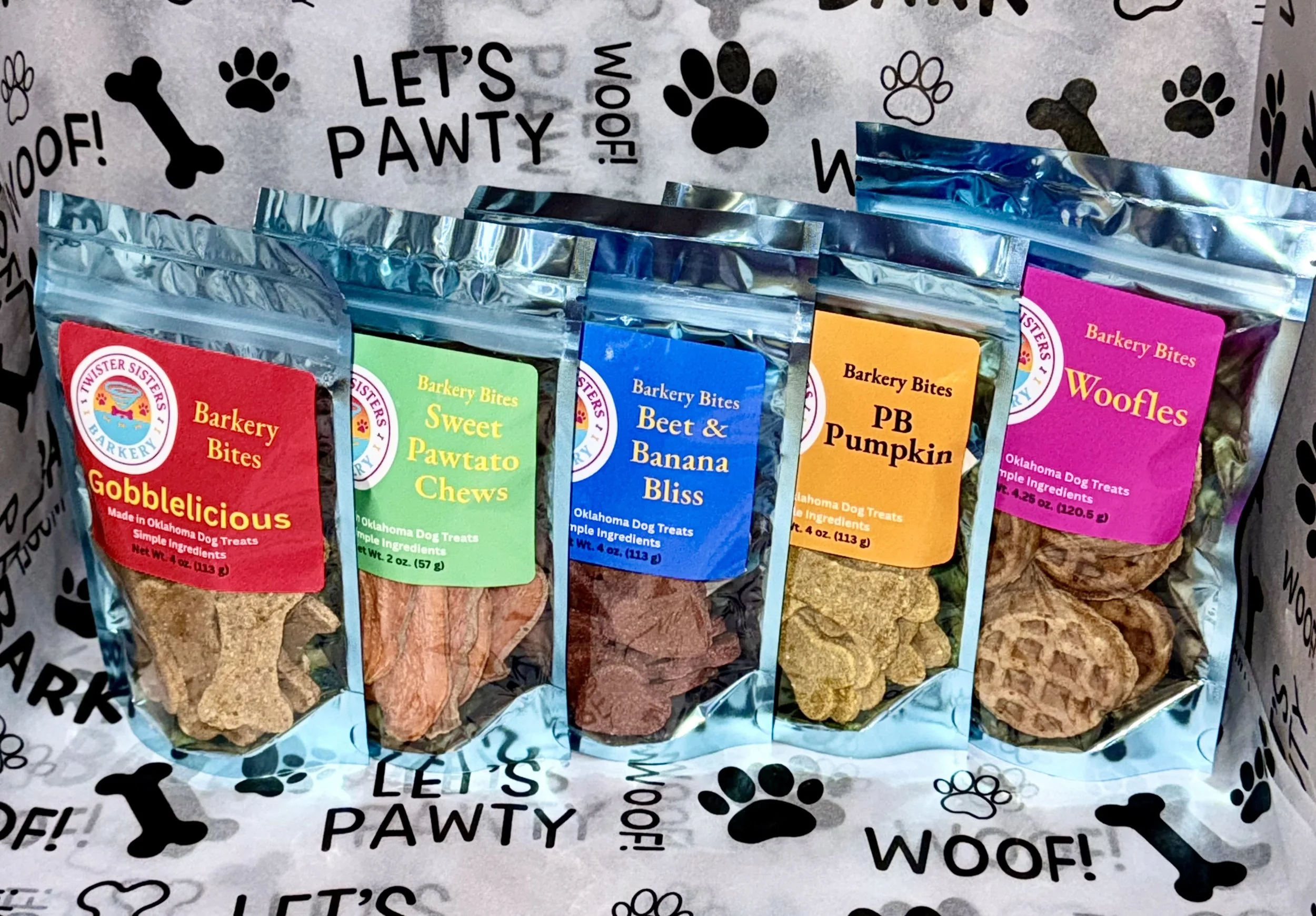 Five colorful resealable bags of dog treats labeled 'Barkery Bites' with different flavors, including Gobblelicious, Sweet Pawtato Chews, Beet & Banana Bliss, PB Pumpkin, and Woofles.