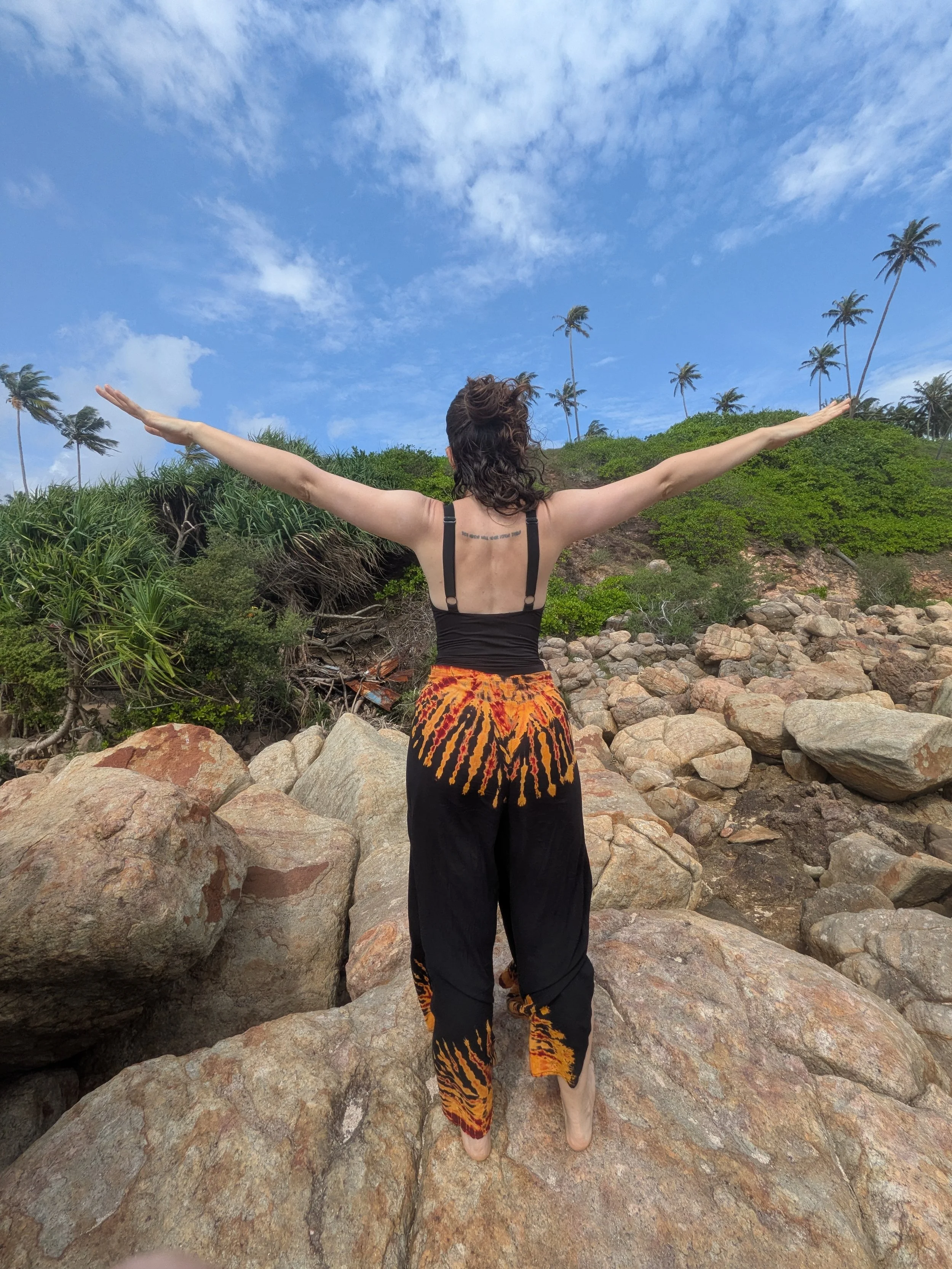 Laura the Utrecht yogi with arms extended, a blue sky and birds