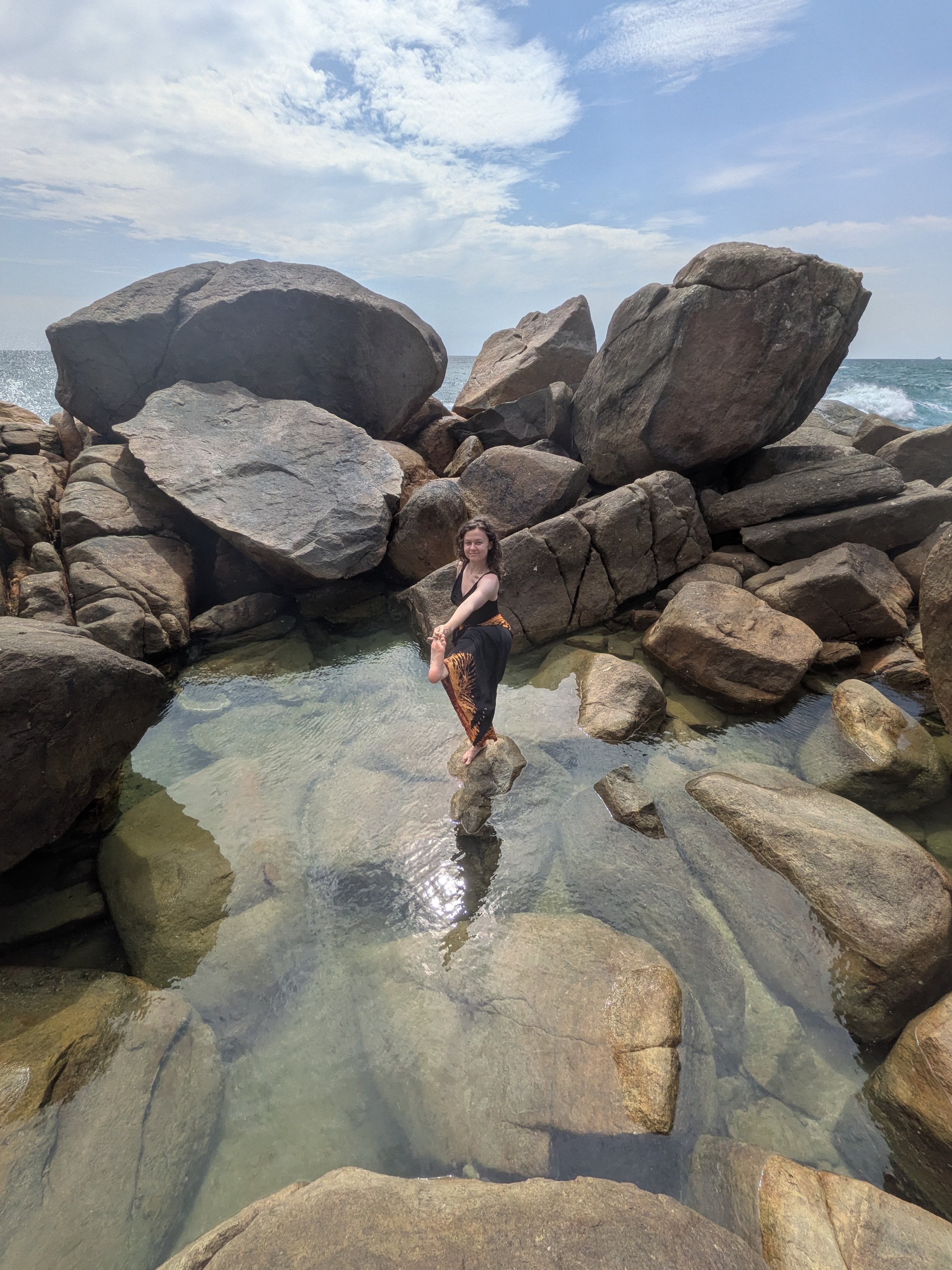 Laura practising yoga on a rocky beach