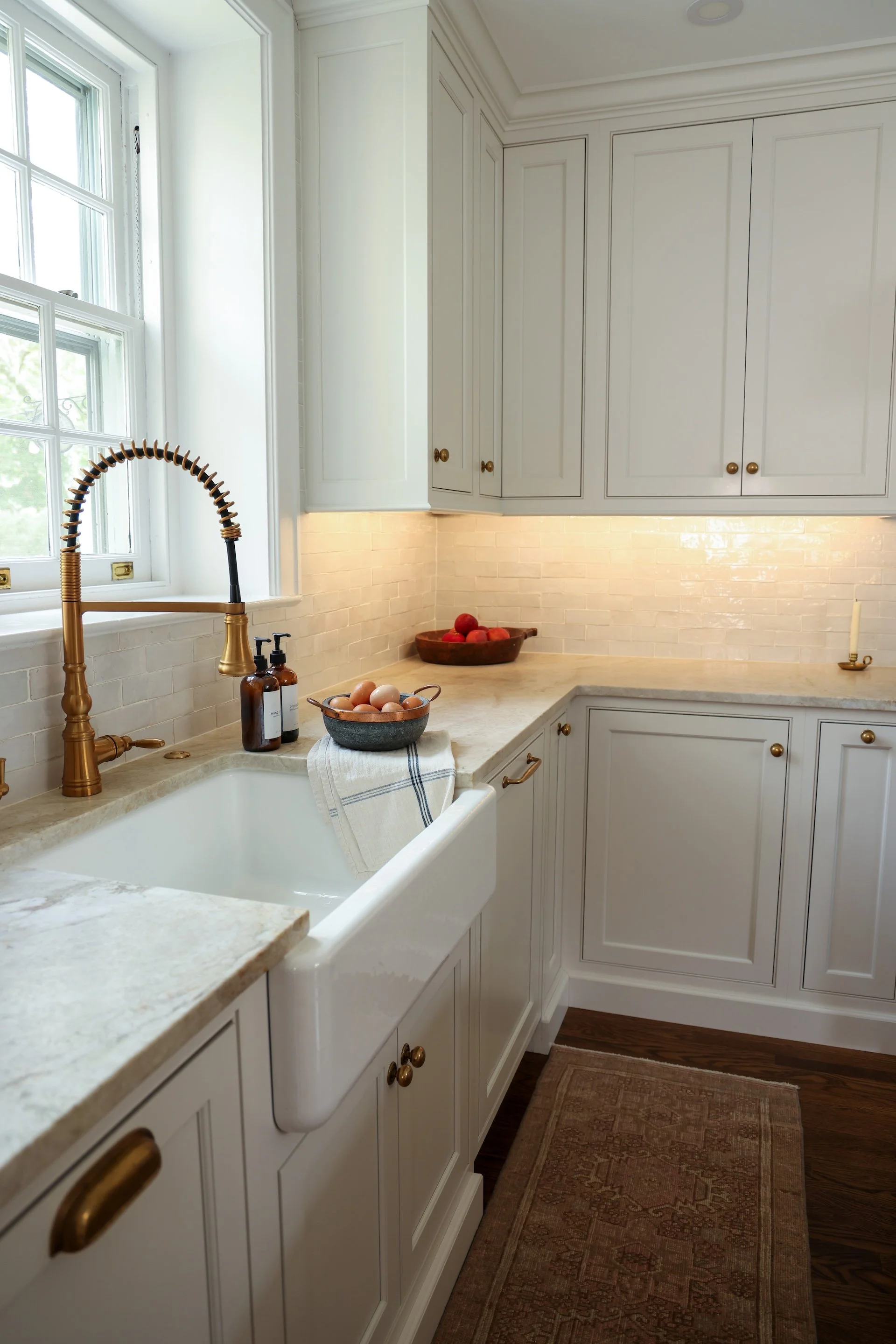 White custom kitchen with golden hardware and farmhouse style sink