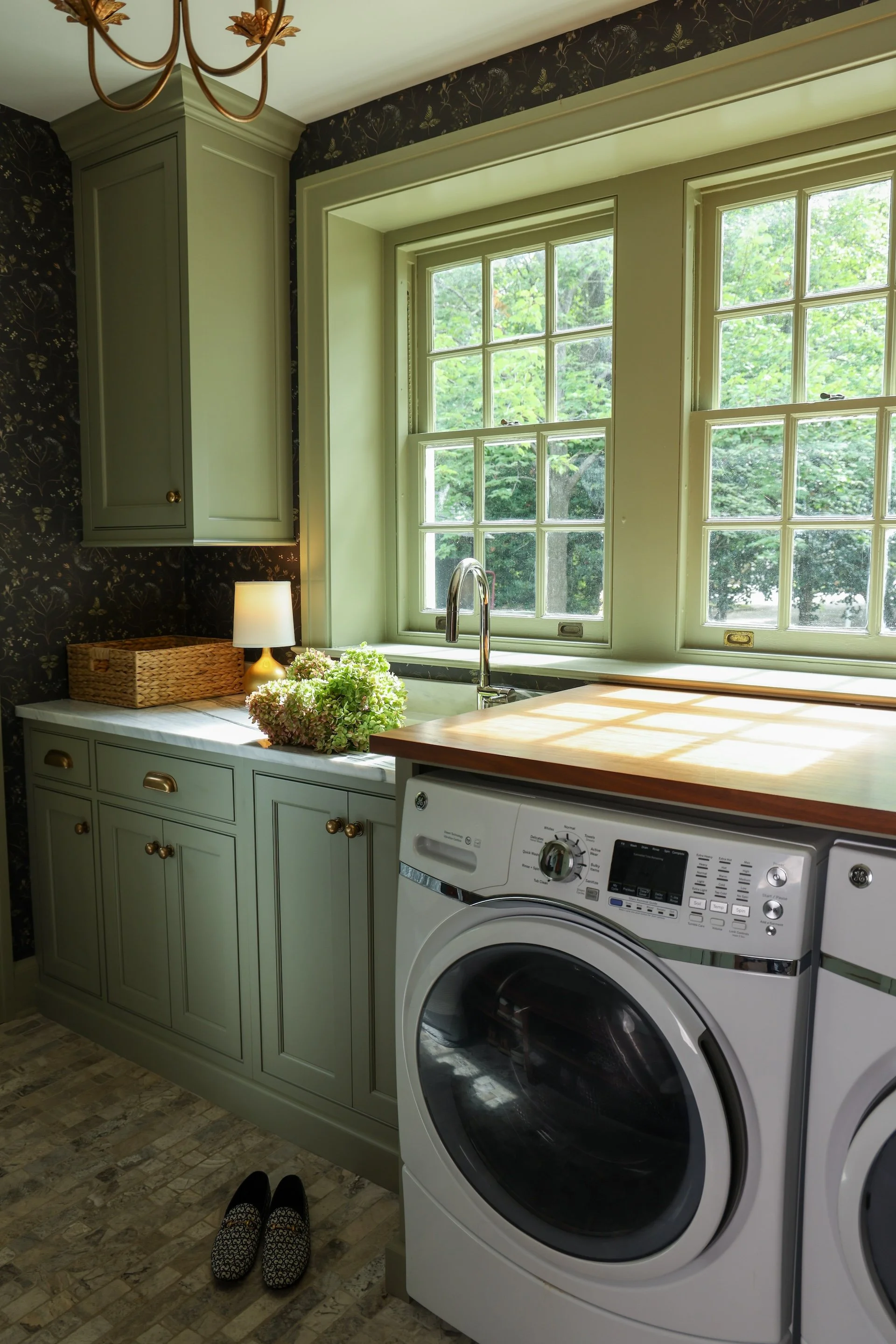 Green custom laundry cabinets with wooden top