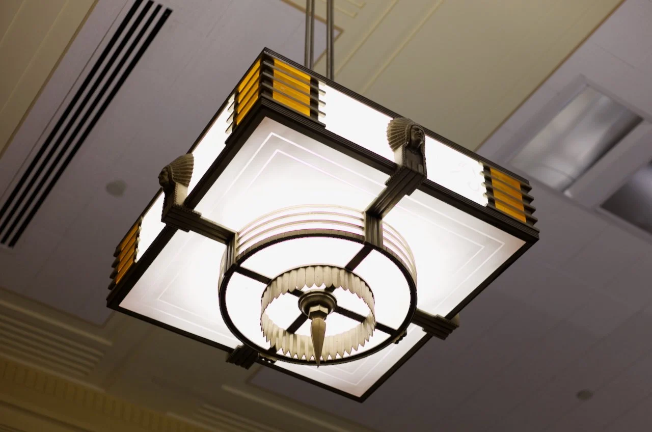 A decorative ceiling light fixture with geometric design and art deco style in a hotel or conference room ceiling.