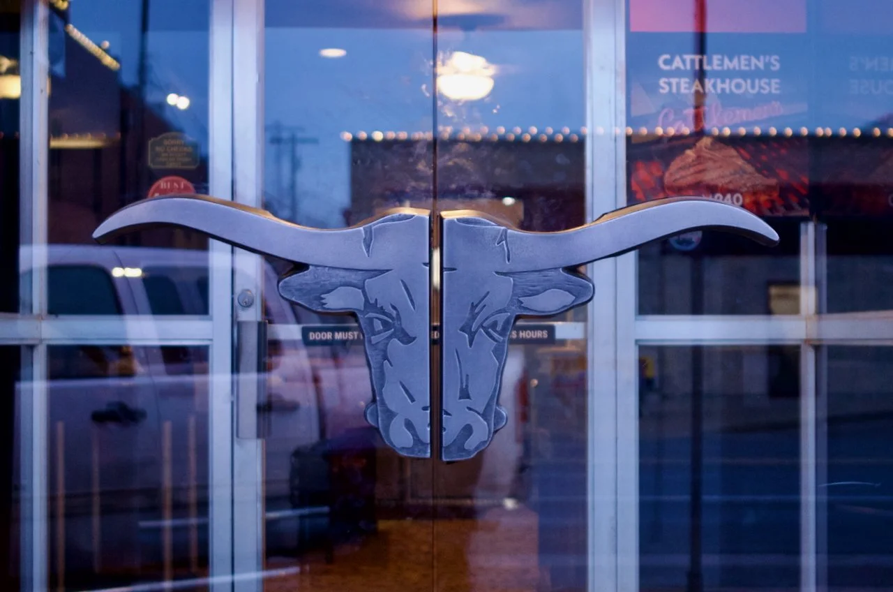 The front door of a restaurant with a longhorn steer head metal door handle.
