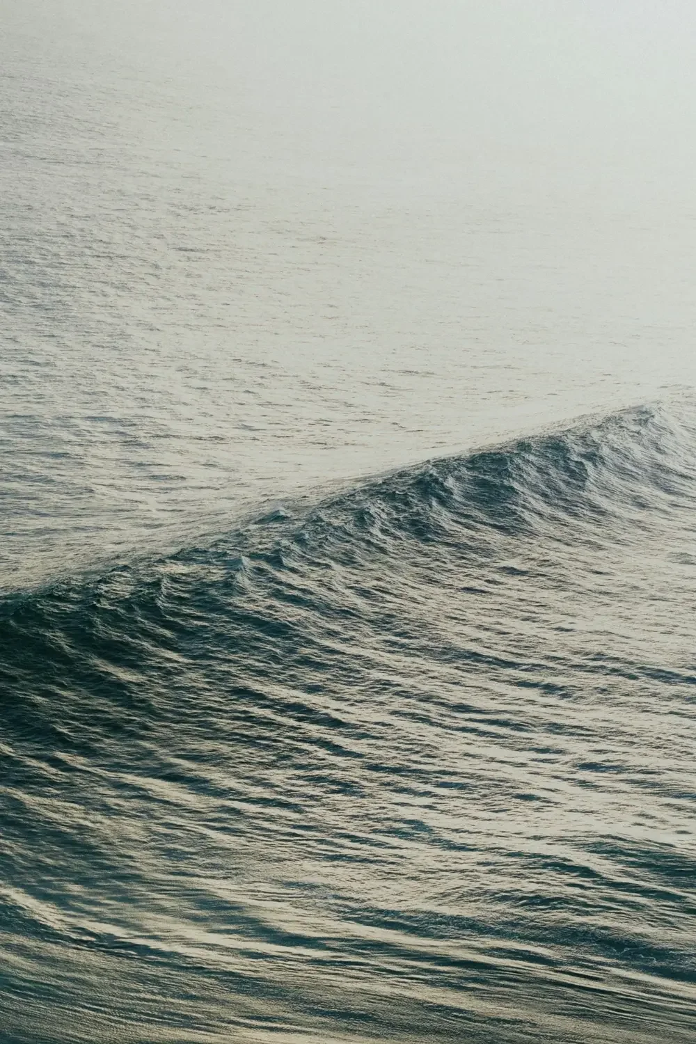 Blick auf das Meer mit leichten Wellen, im Hintergrund eine neblige Atmosphäre.