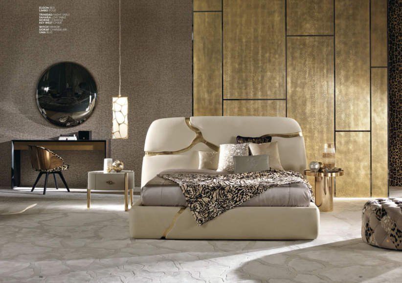 Luxury bedroom with a white bed featuring gold accents, decorative pillows, animal print blanket, gold side tables, a mirror, and leopard print wallpaper.