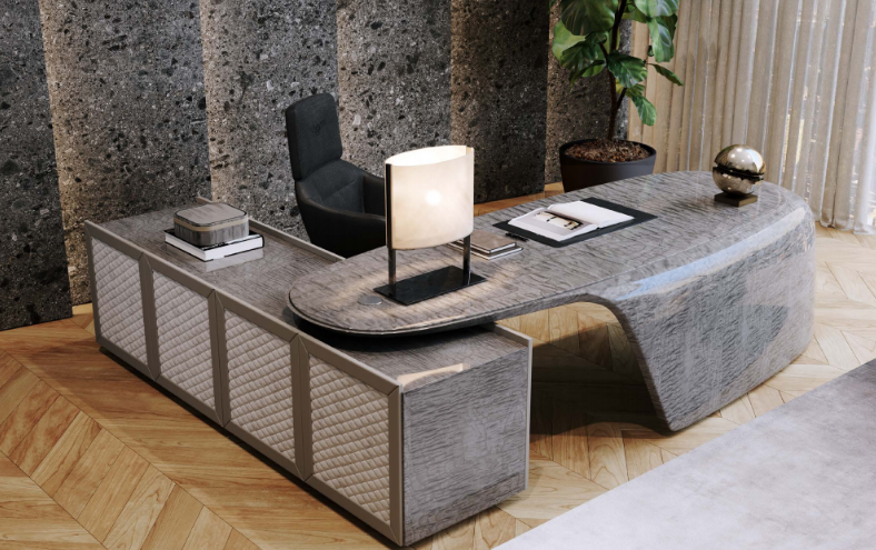 Modern office desk with a black ergonomic chair, lamp, books, and decorative items, set against a stone accent wall and wooden flooring.