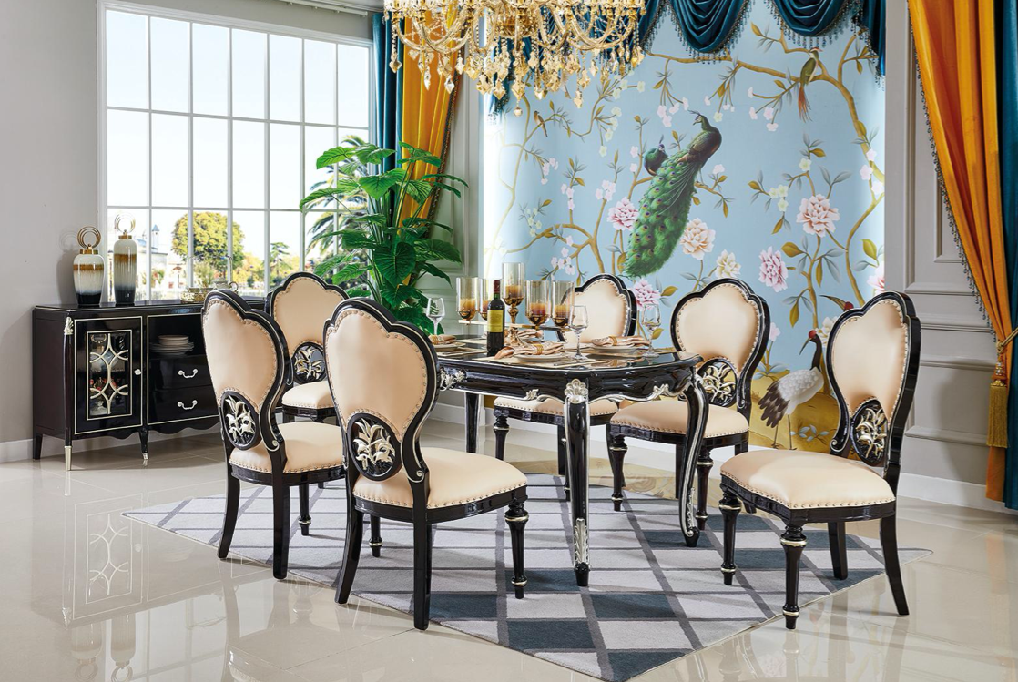 Elegant dining room with a black and beige dining table, seven upholstered chairs, a chandelier, a large window, a potted plant, a decorative mural with peacock and floral designs, and orange and blue curtains.