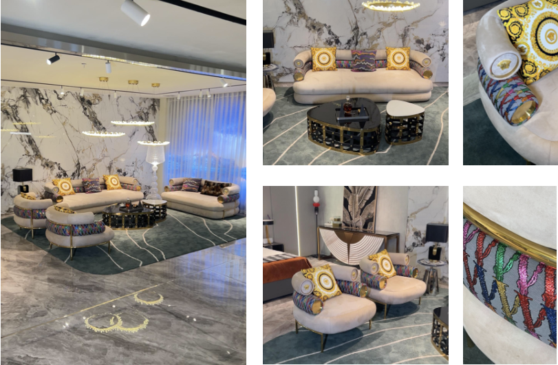 A luxurious living room with marble walls and floors, featuring elegant sofas and armchairs with colorful patterned pillows, a black coffee table, and decorative rugs.
