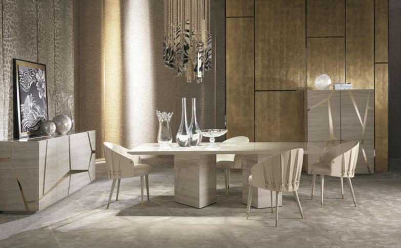 Modern dining room with white marble dining table, six matching chairs, a sideboard with decorative objects, and a gold textured wall.