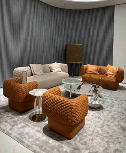 Modern living room with beige and orange sofas, patterned armchairs, a marble coffee table, and a textured blue accent wall.