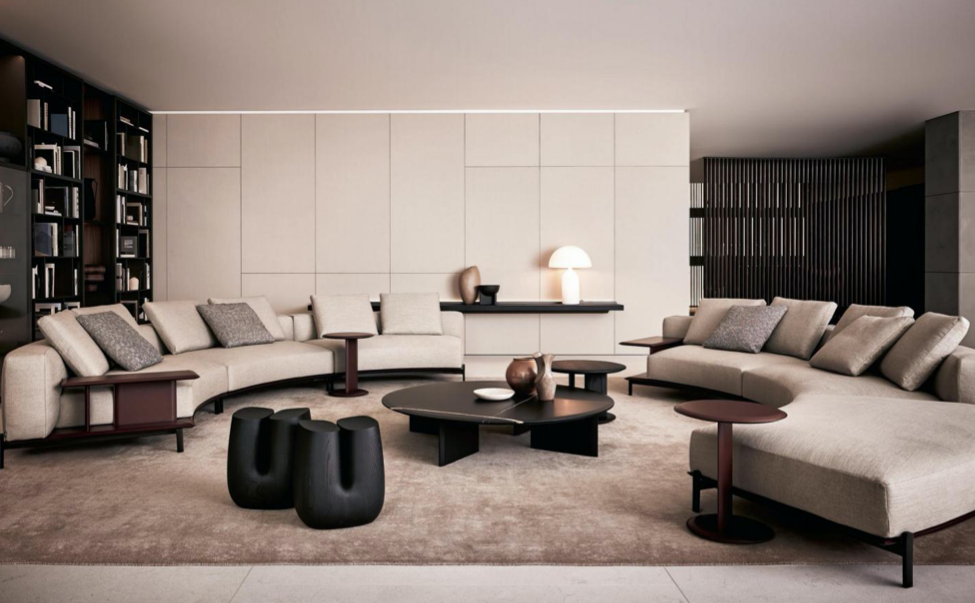 Modern living room with beige sofas, black coffee tables, a built-in bookshelf, and minimal decor.