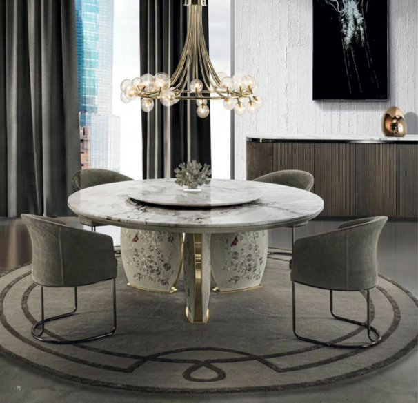 Modern dining room with a round marble table, four gray upholstered chairs, a chandelier with multiple globe bulbs, a sideboard with decorative objects, and large windows with black curtains.