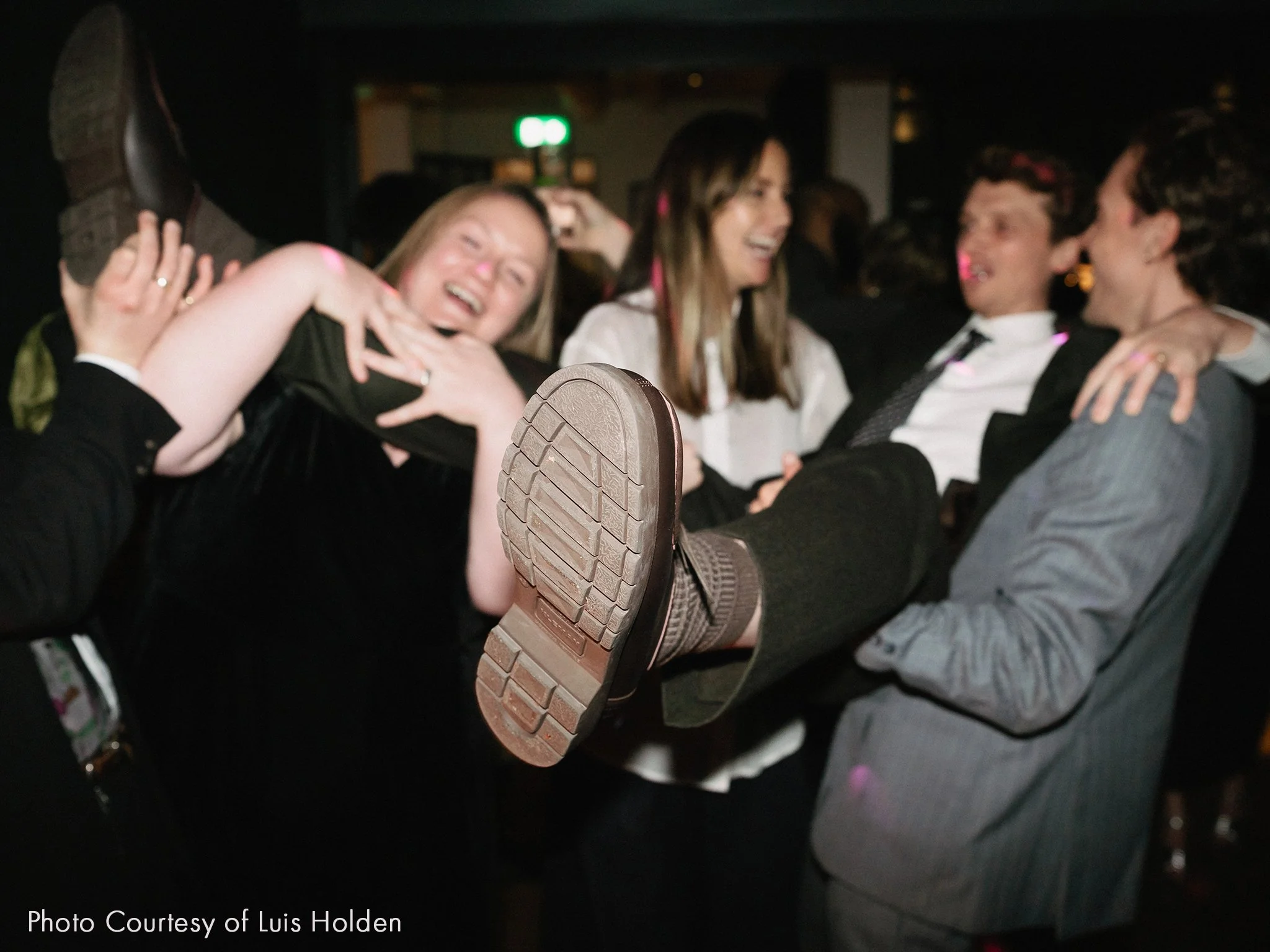 People dancing at a party, with one person in mid-air lifting another person, all smiling and having fun.