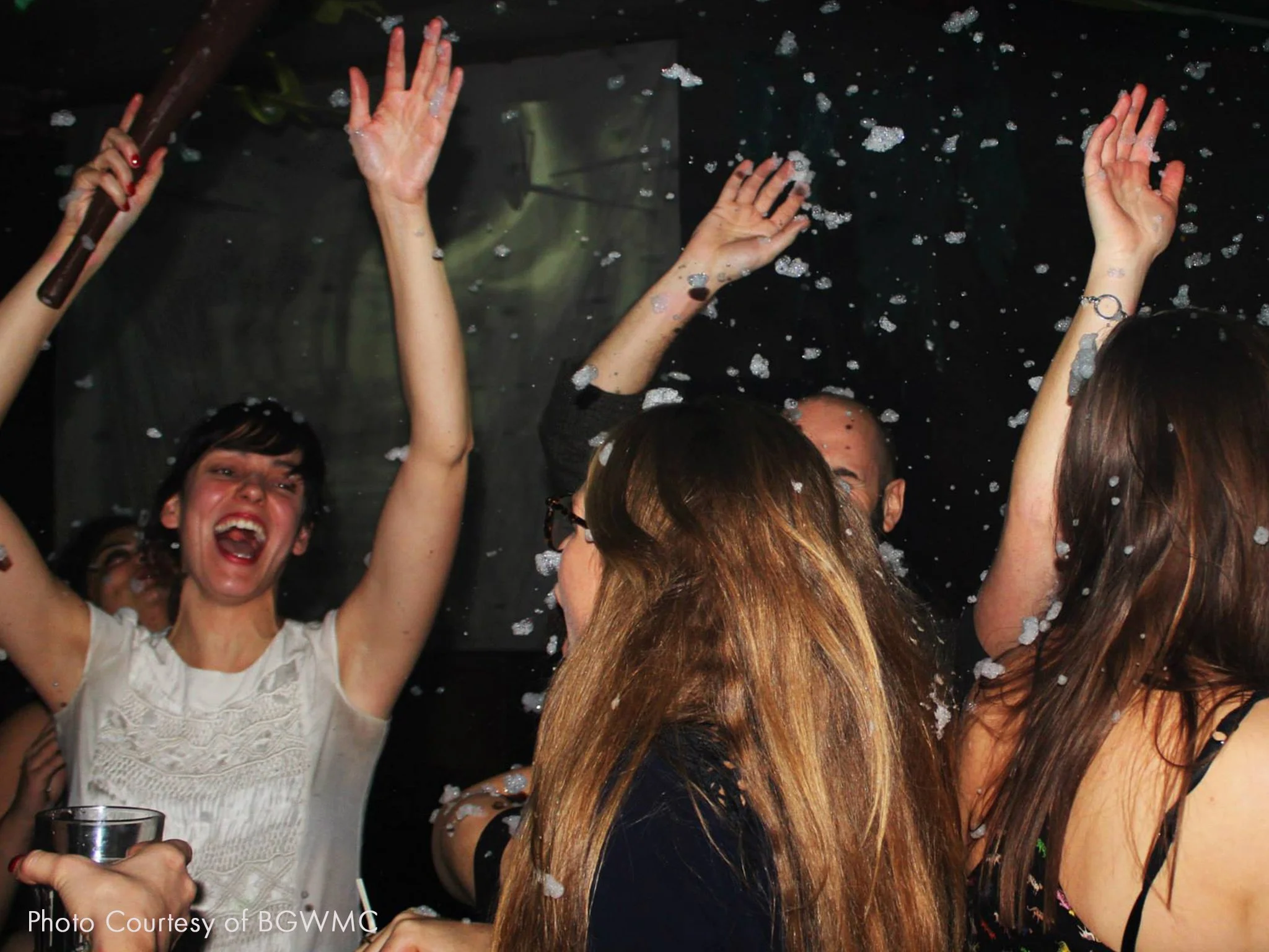 People celebrating at a party with foam, raising their hands and enjoying the moment.
