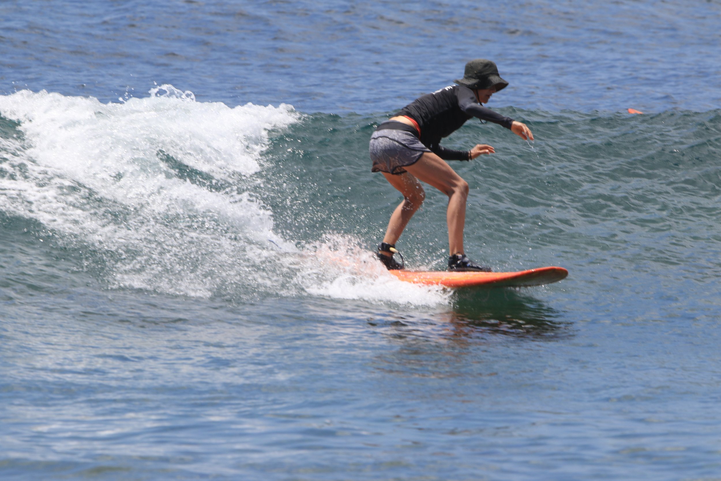Lisa Sanson surfing in the ocean at a yoga retreat