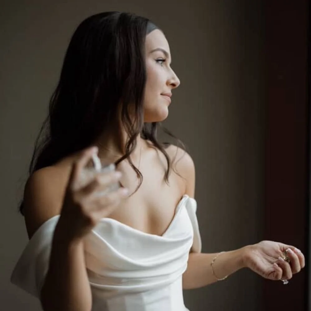 Elegant bride in a natural spray tan spray perfume on herself