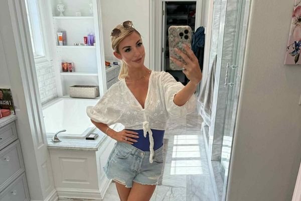 Blonde woman in a white top and shorts with a spray tan