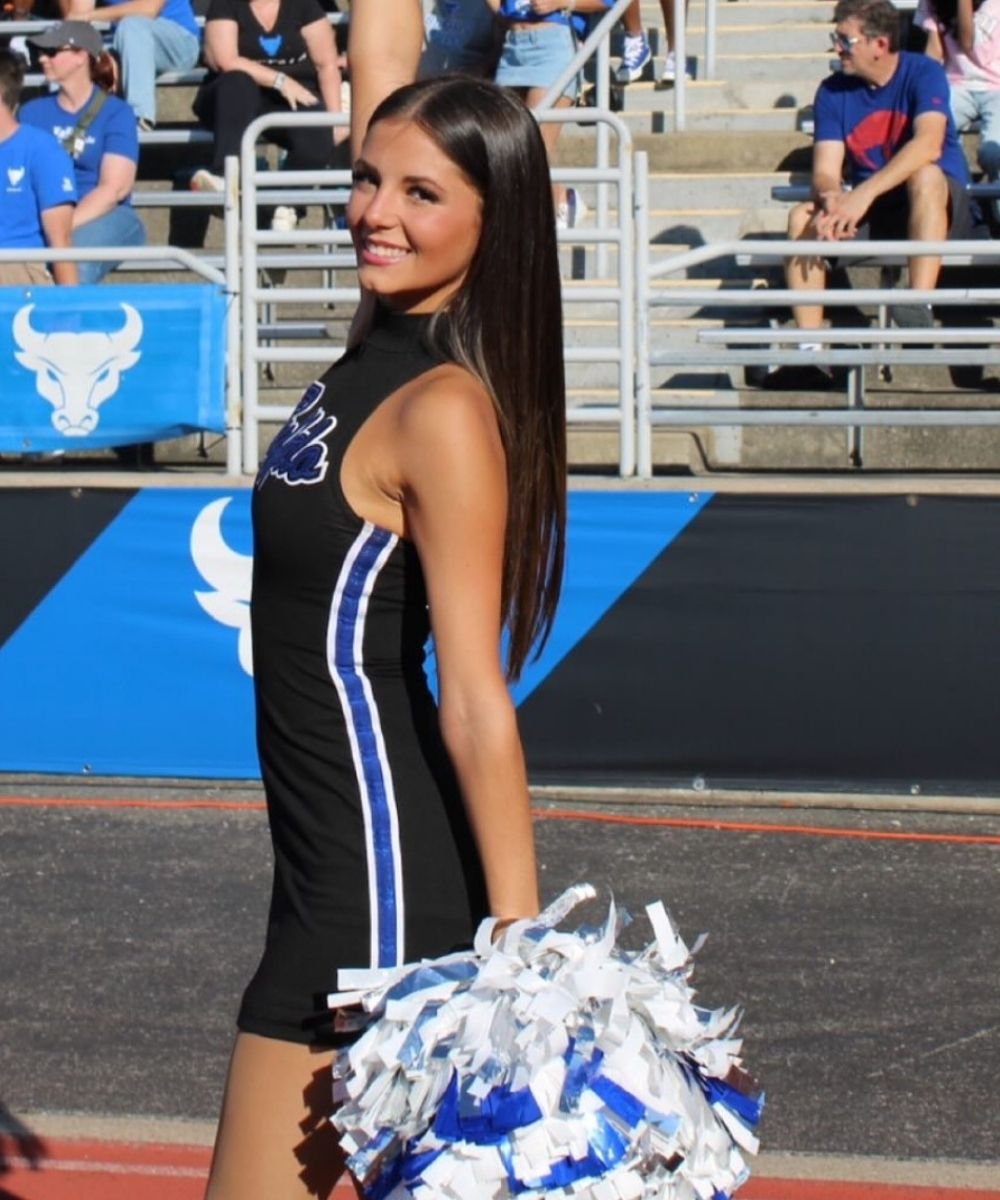 Female UB cheerleader poses on the sidelines with a natural tan