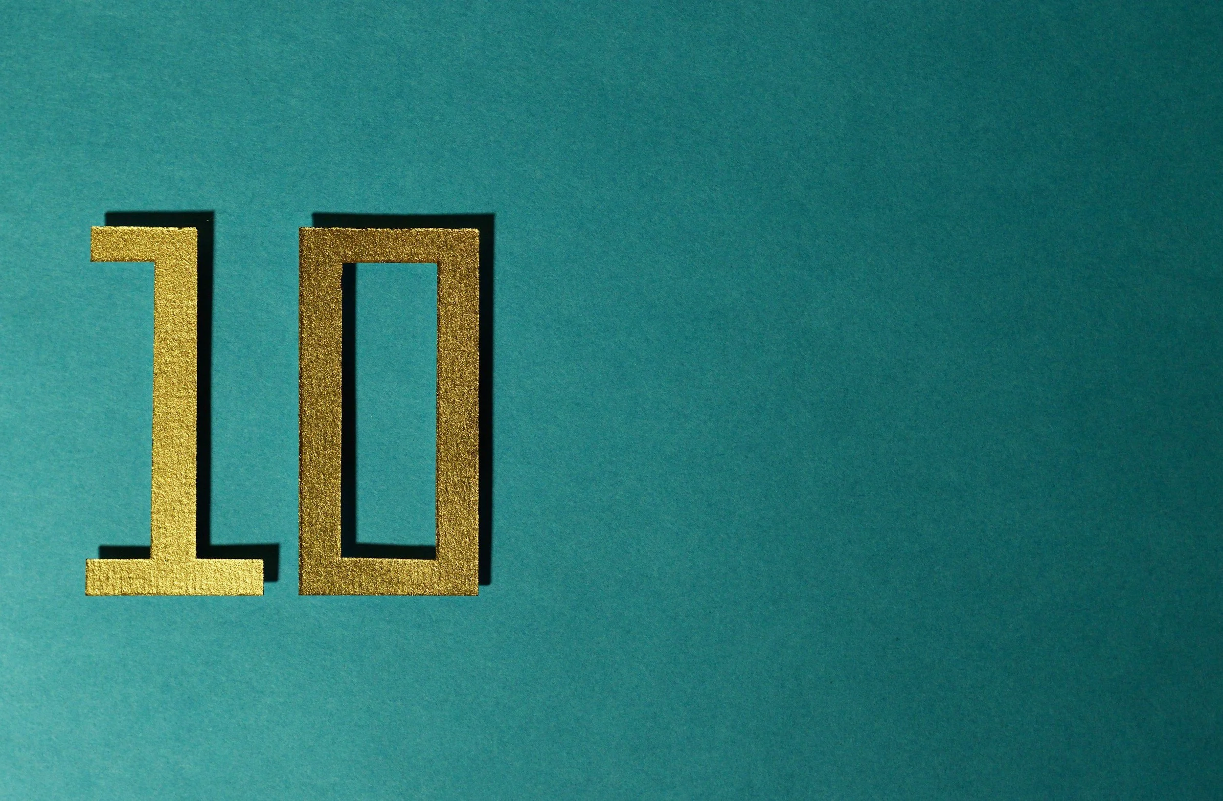 Gold glitter number 10 against a teal background.