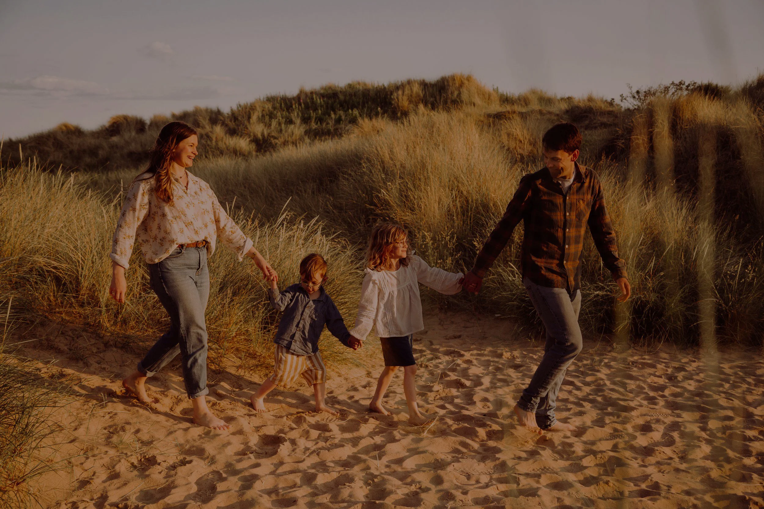 family-holding-hands-through-dunes