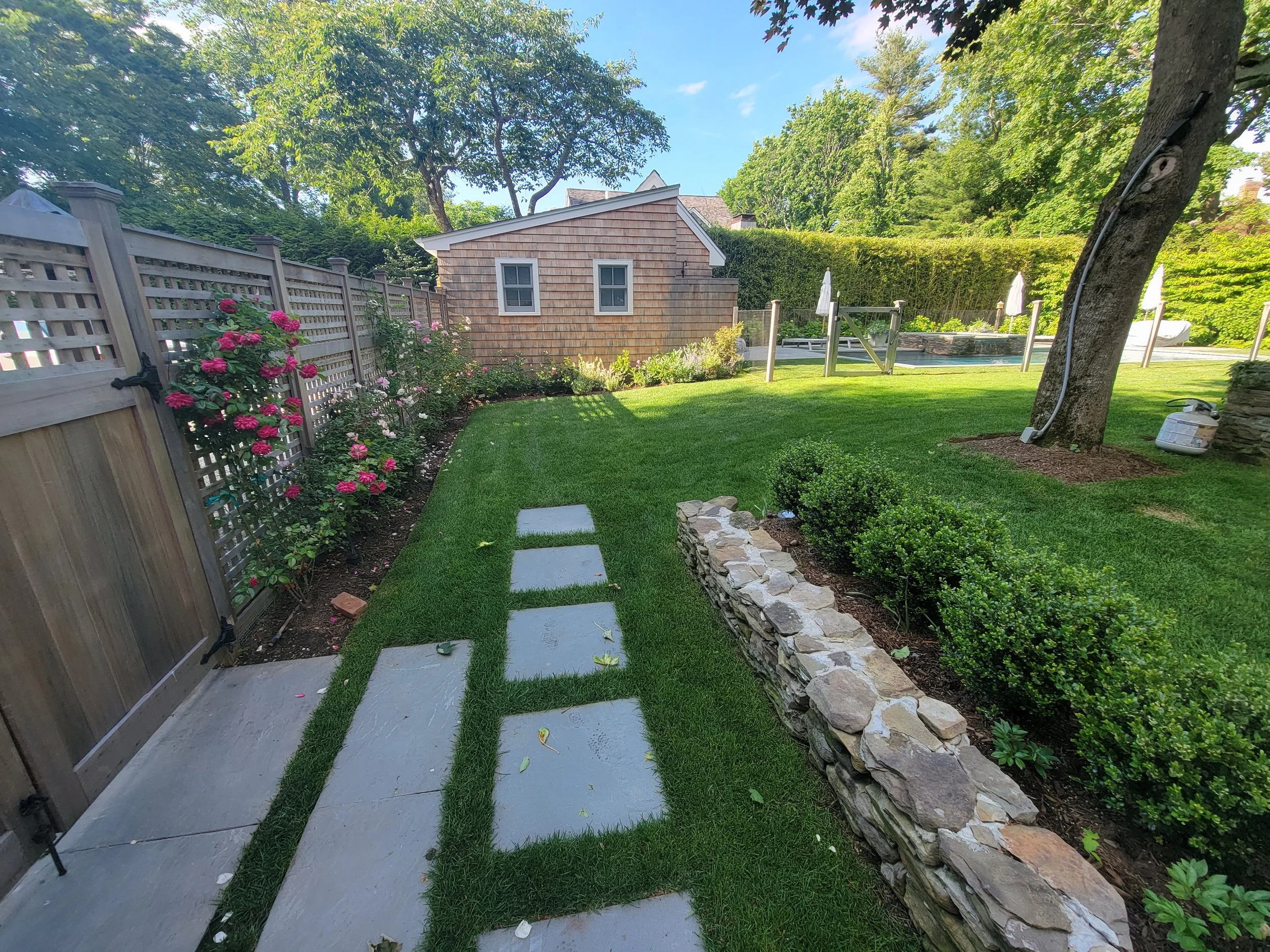 New ornate fencing, walkway, stacked stone retaining wall, bluestone walkway, transplanting and plantings in Bridgehampton NY