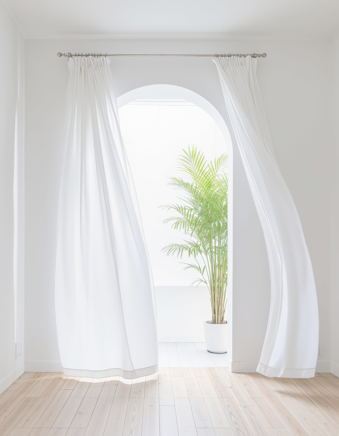 Sheer white curtains blowing in an arched window with soft natural light.
