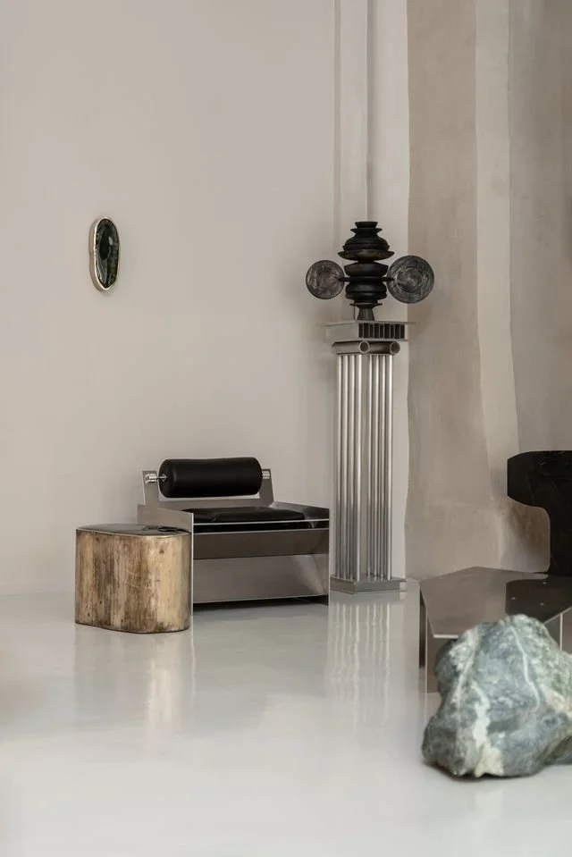 Intérieur moderne avec sculpture, pierre, petit meuble en bois, et élément décoratif noir et argent