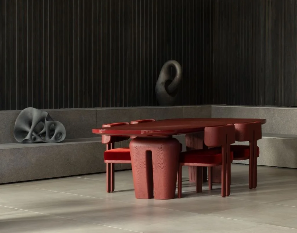 Une salle avec une table en bois rouge et des chaises assorties, décorée avec des sculptures abstraites en noir et gris sur un mur obscur.