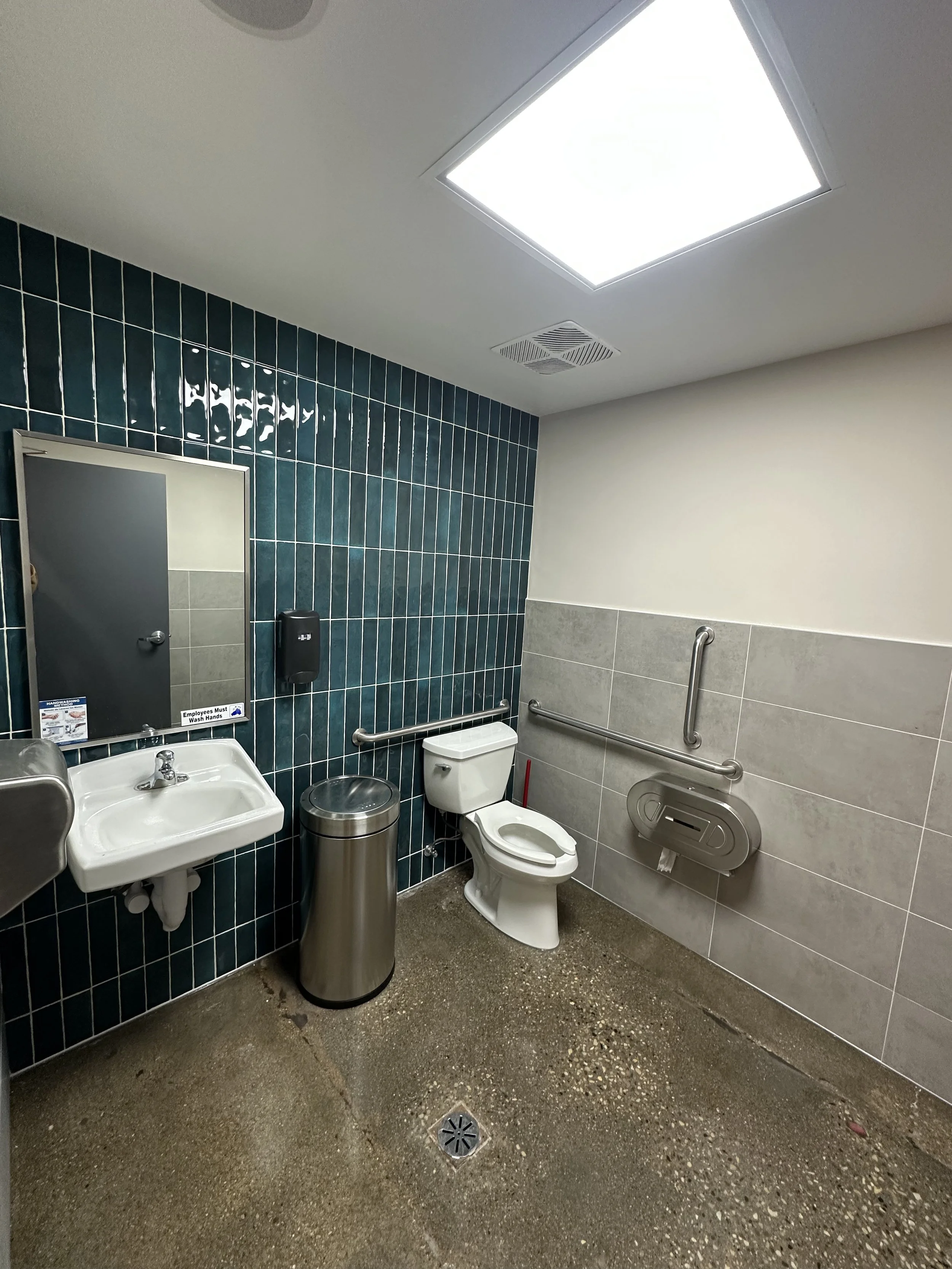 commerical bathroom, teal tile accent wall and gray tile wall, mirror over sink, white toilet