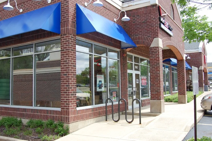 brick exterior of Verizon Wireless store, blue awnings over floor-to-ceiling windows, Verizon Wireless logo above the entryway