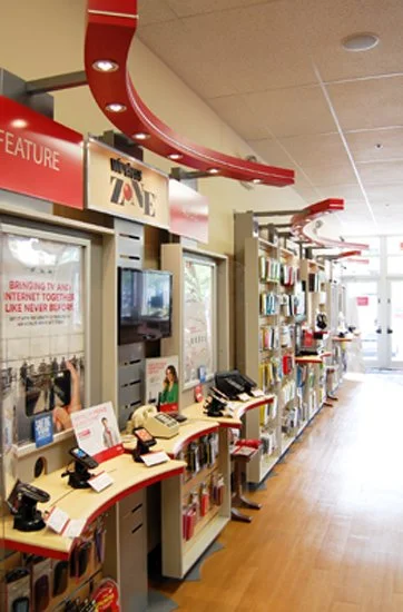 Verizon store interior, phone displays along the wall, red arc lights above displays